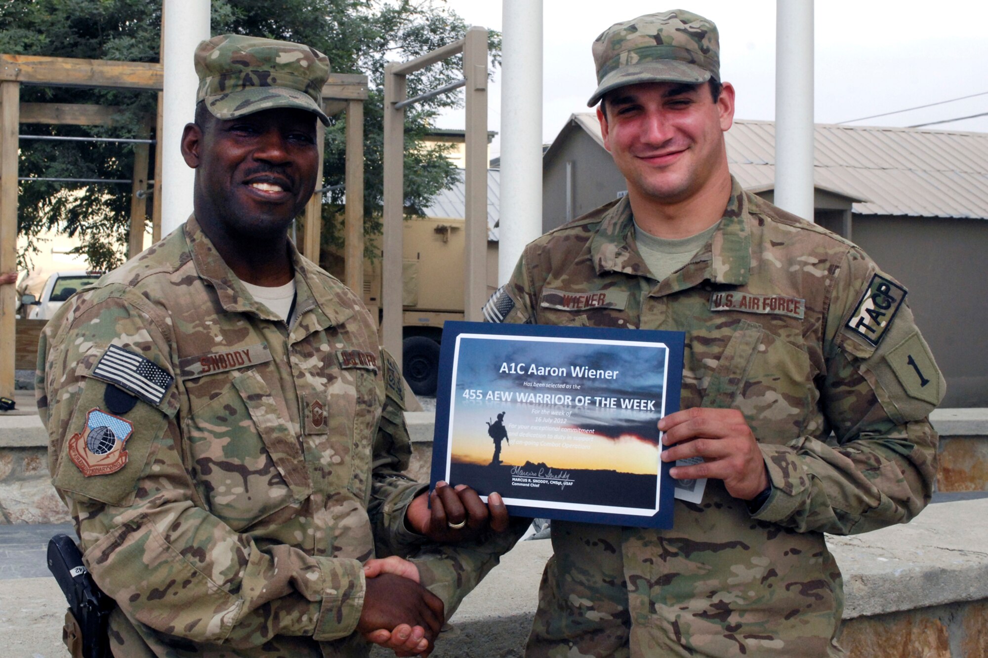Chief Master Sgt Marcus Snoddy, 455th Air Expeditionary Wing command chief, presents the Warrior of the Week award to Airman 1st Class Aaron Wiener, 817th Expeditionary Air Support Operations Squadron Tactical Air Controller Party (or TACP) Journeyman, at Bagram Airfield, Afghanistan, July 17, 2012. Wiener monitors the use of close-air support for seven task forces. He also assists Joint Terminal Attack Controller (or JTAC) in the coordination of close-air support and reconnaissance missions in support of Army ground commander’s scheme of maneuver. (U.S. Air Force photo/SSgt Jeff Nevison)