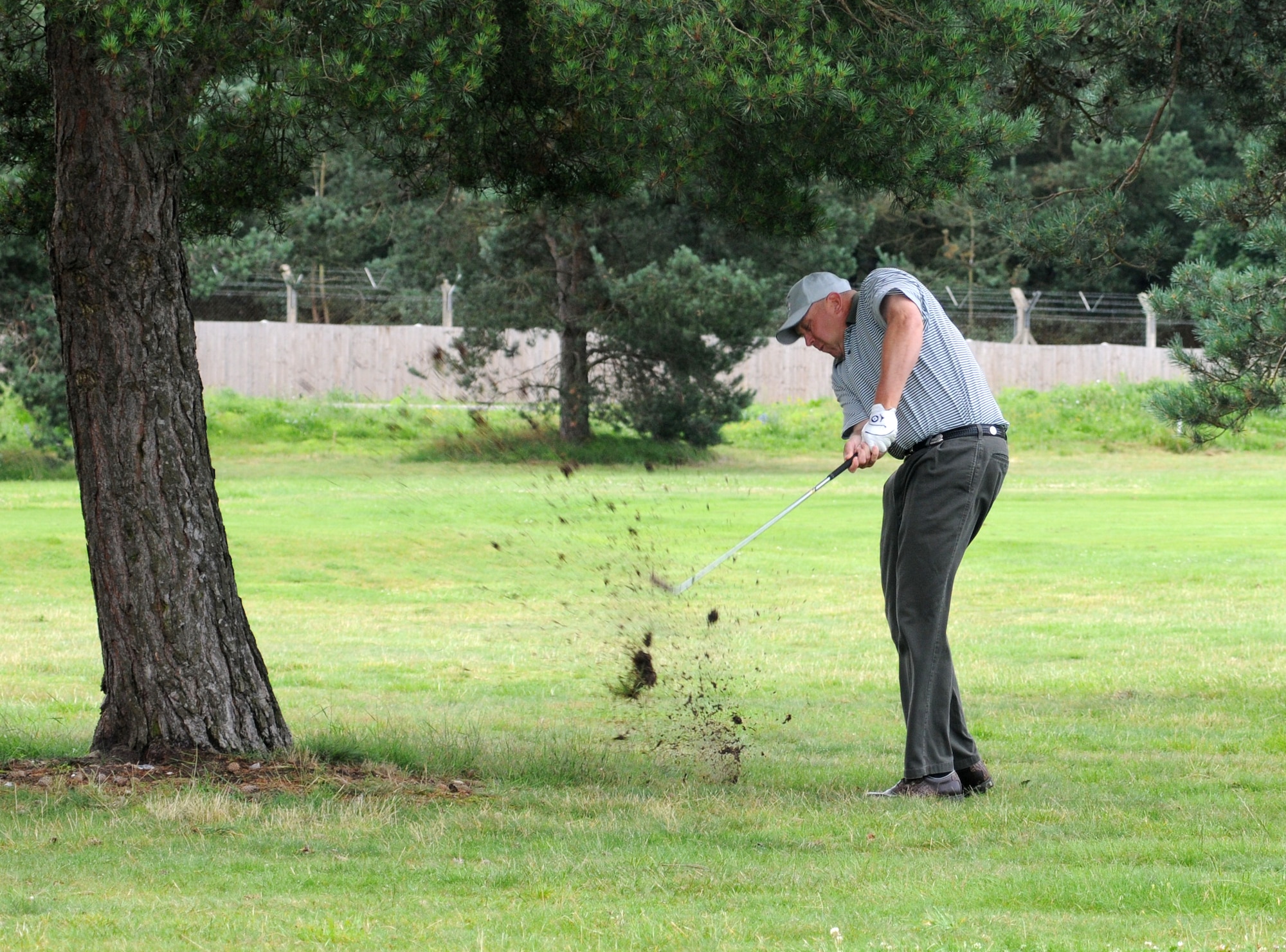 RAF LAKENHEATH, England – John Gibson, 100th Civil Engineer Squadron, plays a punch shot under a tree at the 370-yard par-4 eighth hole during the RAF Mildenhall Intramural Golf playoffs at Breckland Pines Golf Club, RAF Lakenheath, July 17, 2012. The 100th CES stormed into an early lead playing against the100th Maintenance Squadron, A team in the winners bracket with birdies at holes two, three and four. The eighth hole was halved in four, so 100 CES remained 3-up. (U.S. Air Force photo/Gary Rogers)