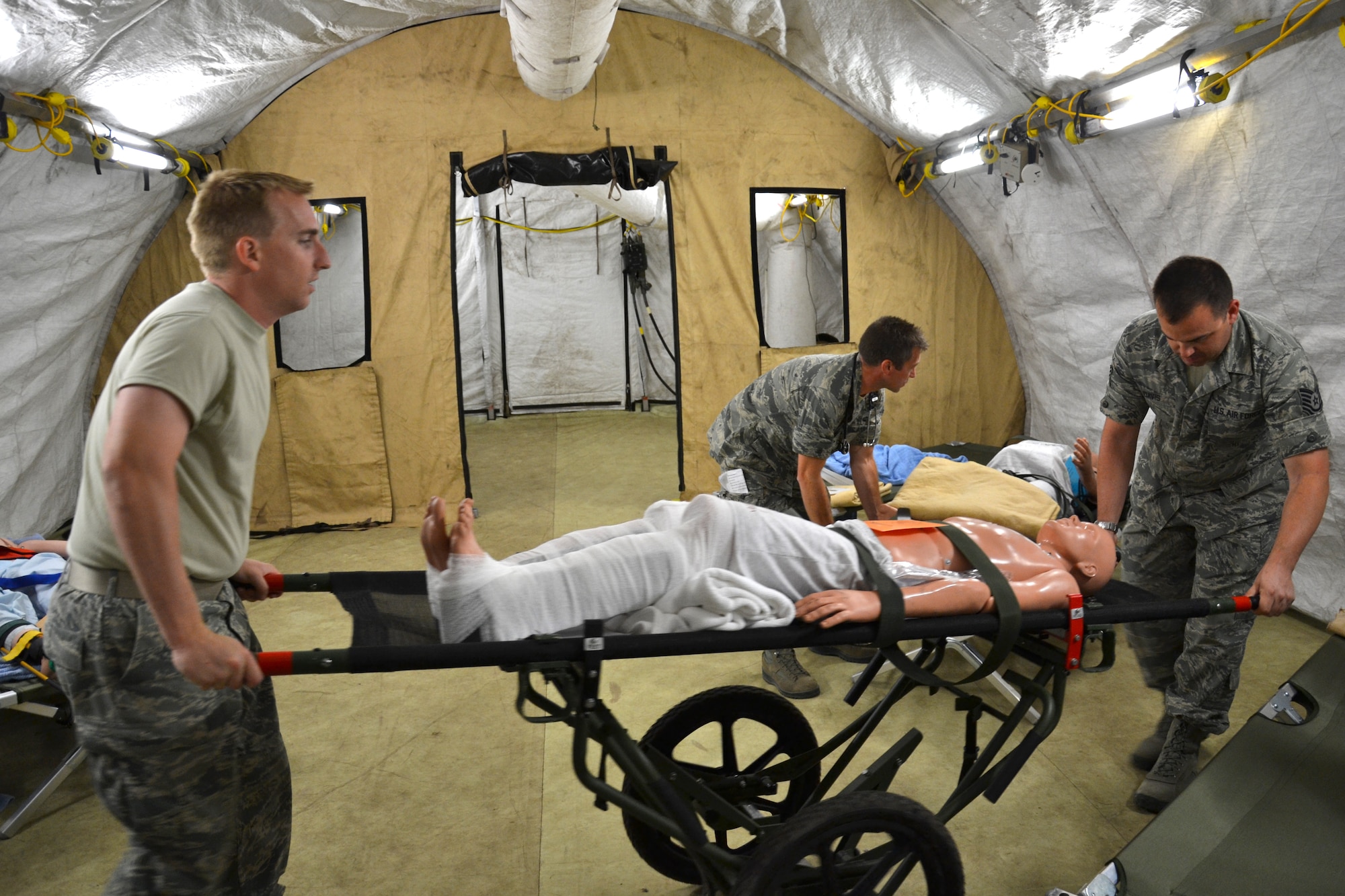 Tech. Sgt. Danny Watton and Tech. Sgt. Travis Davis, medical technicians from the Arizona Air National Guard’s 162nd Medical Group, transport a mock patient with a bi-lateral femur fracture from the emergency room to the ward in an Expeditionary Medical Support field hospital. The medical technicians were participating in “real world” exercises at the Alpena Combat Readiness Training Center in Michigan. (U.S. Air Force photo/Master Sgt. Cally Handa)