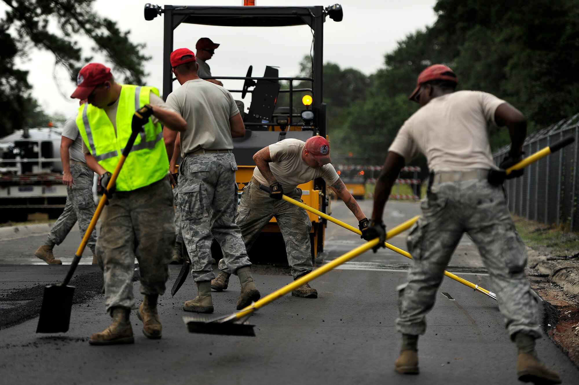 U.S. Air Force Airmen assigned to the 823rd RED HORSE Squadron, sweep, shovel and rake as they perfect freshly laid asphalt on Aiken Street, Shaw Air Force Base, S.C., July 12, 2012. A team of 21 Airmen assigned to the 823rd RHS are slated to repave just over a mile of Shaw roadway. The 823rd RHS is an Air Combat Command asset assigned to the Ninth Air Force that operates out of Hurlburt Field, Fla. RED HORSE stands for Rapid Engineer Deployable Heavy Operational Repair Squadron Engineer. (U.S. Air Force photo by Senior Airman Kenny Holston/Released)  