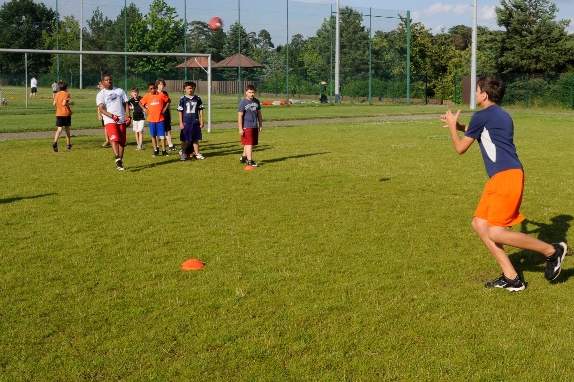 Athletes practice throwing and catching a football during the youth football camp on Ramstein Air Base, Germany, July 10, 2012. The camp is aimed at teaching the participants football techniques. (U.S. Air Force photo/ Senior Airman Aaron-Forrest Wainwright)