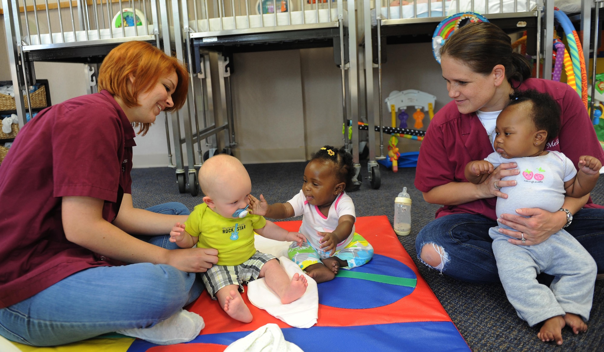 Melissa Bryant and Melissa Grice, both room lead teachers, play with infants July 10, at Little Rock Air Force Base Ark. The infant room takes six week to one year olds for military and non-military parents who work at Little Rock Air Force Base. (U.S. Air Force photo by Airman 1st Class Ellora Remington)