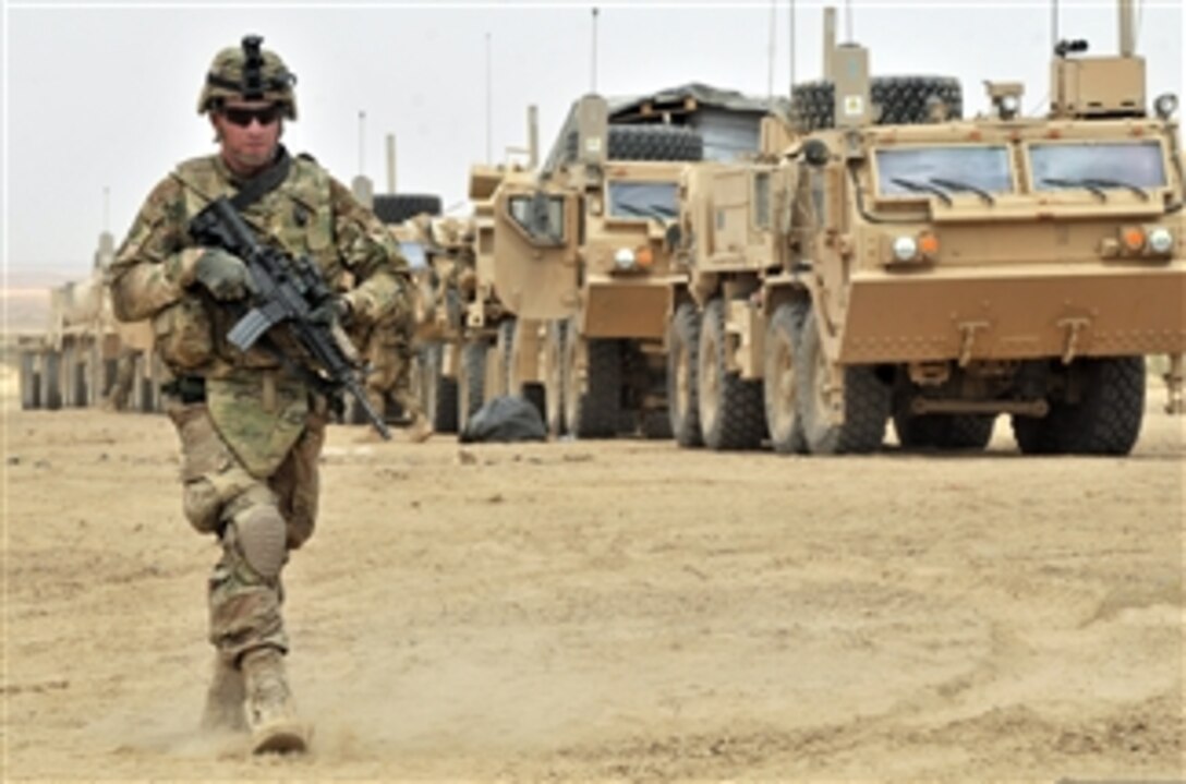 U.S. Army Cpl. Bruce Sexton walks along a line of vehicles during Operation Buffalo Thunder II in the district of Shorabak, Afghanistan, on June 28, 2012.  During the eight-day mission, Afghan and American forces cleared more than 120 kilometers of terrain and escorted about 60 truckloads of humanitarian aid for distribution to the people of Shorabak