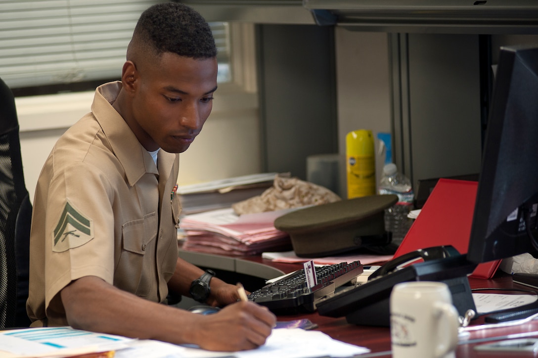 Cpl. Sirin Broadus, supply administration clerk with Marine Barracks Washington, fills out paperwork at his desk July 17.