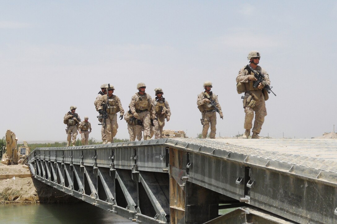 Marines with the Personal Security Detachment, 1st Marine Logistics Group (Forward), cross a bridge in Helmand Province, Afghanistan, while escorting Brig Gen. John J. Broadmeadow, Commanding General, 1st MLG (Fwd). The PSD team, who is responsible for the security of the commanding general during his trips, has completed 33 ground missions and travelled nearly 4,000 miles throughout the area of operations.
