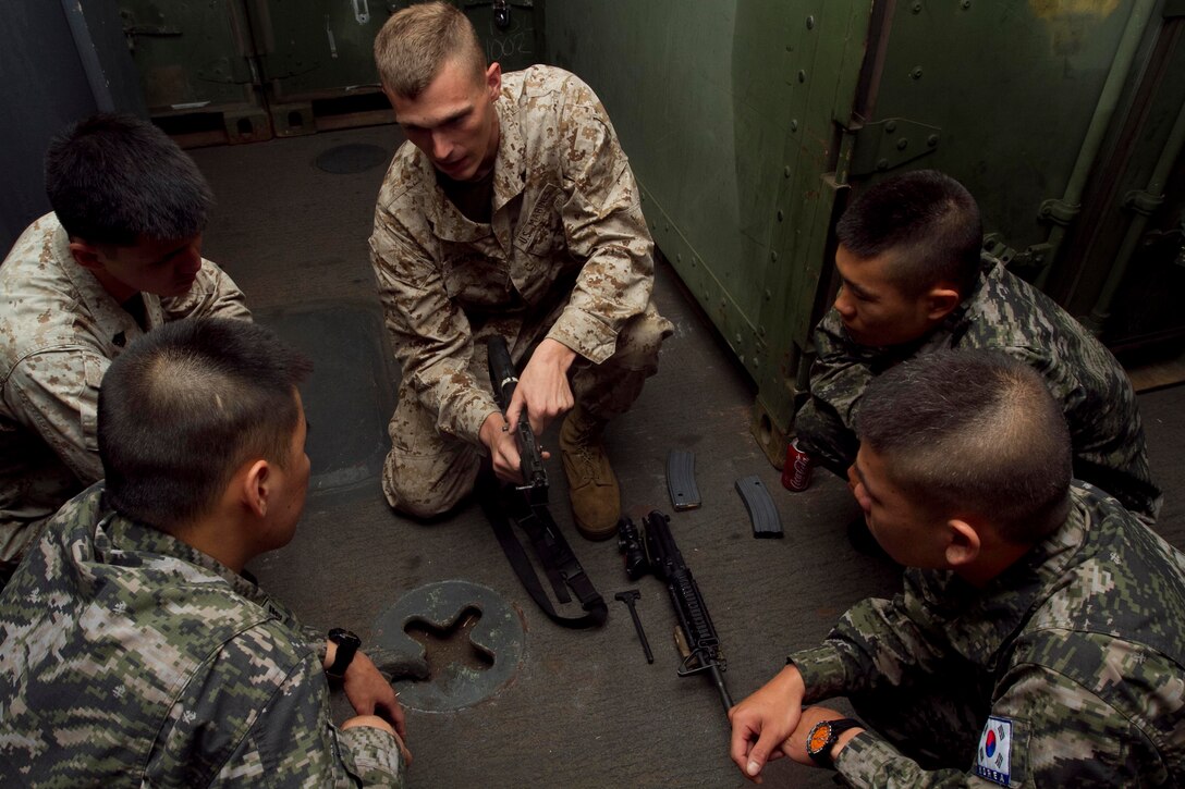 PACIFIC OCEAN -U.S. Marine Cpl. Jonathan Macqueen speaks to Republic of Korea Marines visiting USS New Orleans and embarked members of the 11th Marine Expeditionary Unit here June 3 during a weapons class. The 25-year-old hails from Hudsonville, Mich., and serves as a rifleman with Headquarters and Service Company, Battalion Landing Team 3/1. The landing team serves as the ground combat element for the unit. The visitors boarded the ship to sail to Hawaii for the Korean Marine Exercise Program 12-9, a regularly scheduled combined exercise involving a platoon of Republic of Korea Marines from 1st Company, 21st Battalion, 1st Marine Division, and U.S. Marine forces from 1st Battalion, 3rd Marines. This exercise will focus on strengthening the ROK-U.S. relationship while enhancing tactical interoperability and developing ROK Marine operational capabilities. , Cpl. Ryan Carpenter, 6/2/2012 8:00 PM