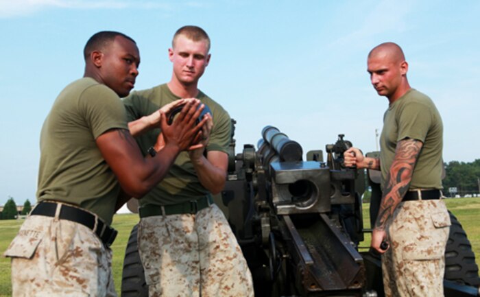 (From left) Sgt. Tory Fontenette, Lance Cpl. Chris Griggs, and Sgt. William Mullen, 3rd Battalion, 10th Marines, practice loading drills on the M101A1 Howitzer which fires every year in conjunction with the 2nd Division Marine Band's rendition of the William Tell "Overture." The Marines worked during the holiday week in preparation for the Fourth of July Celebration on W.P.T. Field aboard Marine Corps Base Camp Lejeune.