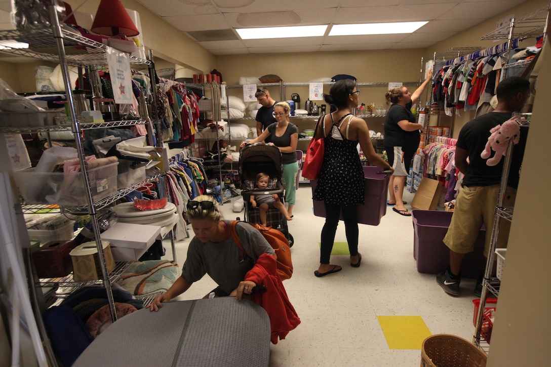 Military family members look through a plethora of goods to put in their totes during the Backdoor Boutique hosted at the Armed Services YMCA aboard Marine Corps Base Camp Lejeune’s Tarawa Terrace residential area July 14. Participants had a wide selection of wares available to them such as canned foods, kitchen ware, clothes, toys and bed dressings. 