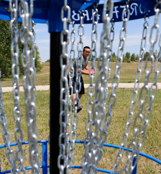 Airman 1st Class Daniel Miller, 28th Operations Support Squadron air traffic control technician, aims at the basket while playing disc golf at Ellsworth Air Force Base, S.D., July 13, 2012. The 28th Force Support Squadron Outdoor Recreation Center allows Airmen and their families to borrow discs to play on the base disc golf course course. For more information, call (605) 385-2999. (U.S. Air Force photo by Airman 1st Class Alystria Maurer/Released)