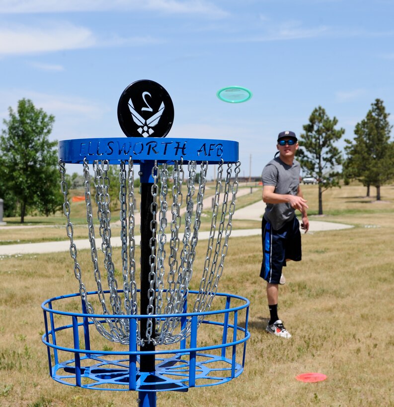 With a flick of his wrist, Airman 1st Class Holdon Rivere, 28th Operations Support Squadron air traffic control technician, puts his disc into the second hole basket on the base disc golf course at Ellsworth Air Force Base, S.D., July 13, 2012. There are three different types of discs available for rent at the 28th Force Support Squadron Outdoor Recreation Center. (U.S. Air Force photo by Airman 1st Class Alystria Maurer/Released)