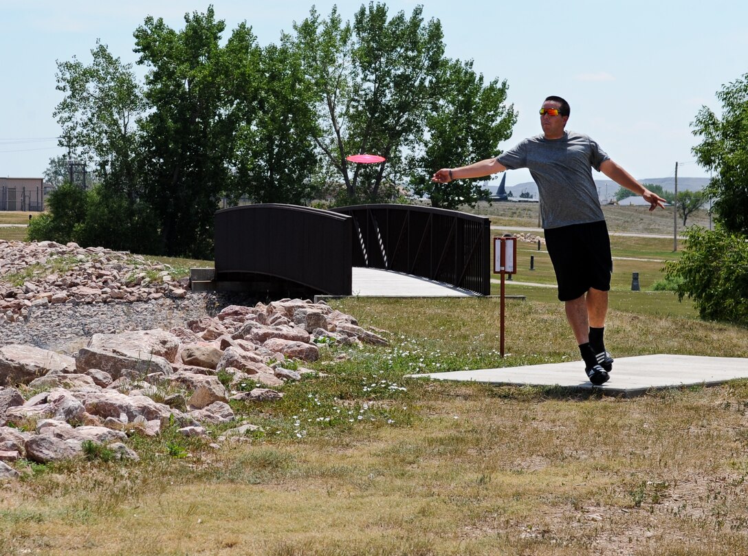 Airman 1st Class Daniel Miller, 28th Operations Support Squadron air traffic control technician, throws his disc toward the basket while playing disc golf at Ellsworth Air Force Base, S.D., July 13, 2012. Ellsworth has an 18 hole disc golf course available for Airmen and their families. (U.S. Air Force photo by Airman 1st Class Alystria Maurer/Released)