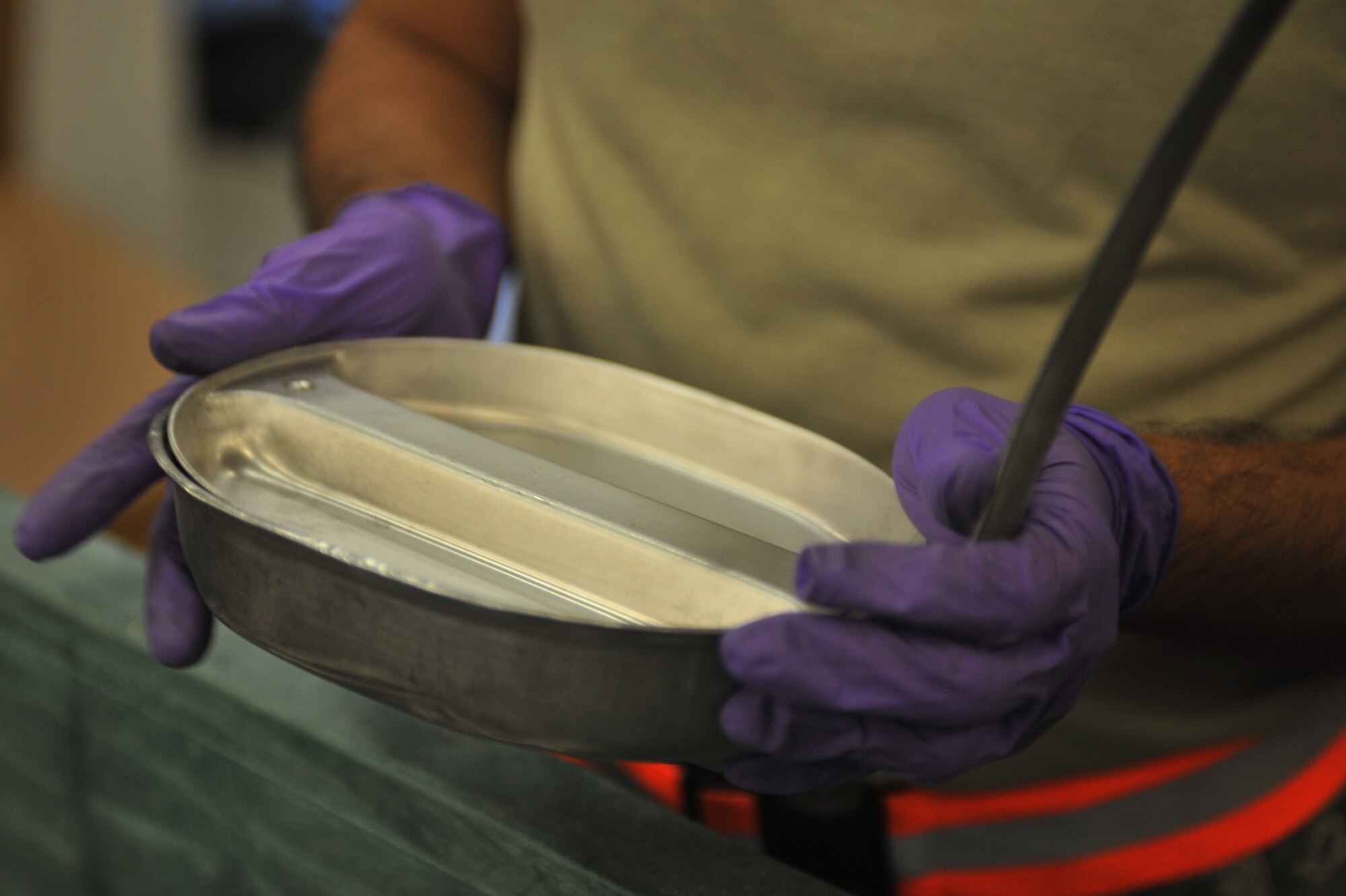 U.S. Air Force Staff Sgt. Santos Delacruz, 27th Special Operations Logistics Readiness Squadron material management flight, holds a mess kit at Cannon Air Force Base, N.M., July 18, 2012. The need for mess kits to serve military rations is no longer necessary, as they were replaced by Meals, Ready to Eat. (U.S. Air Force photo/Airman 1st Class Eboni Reece)