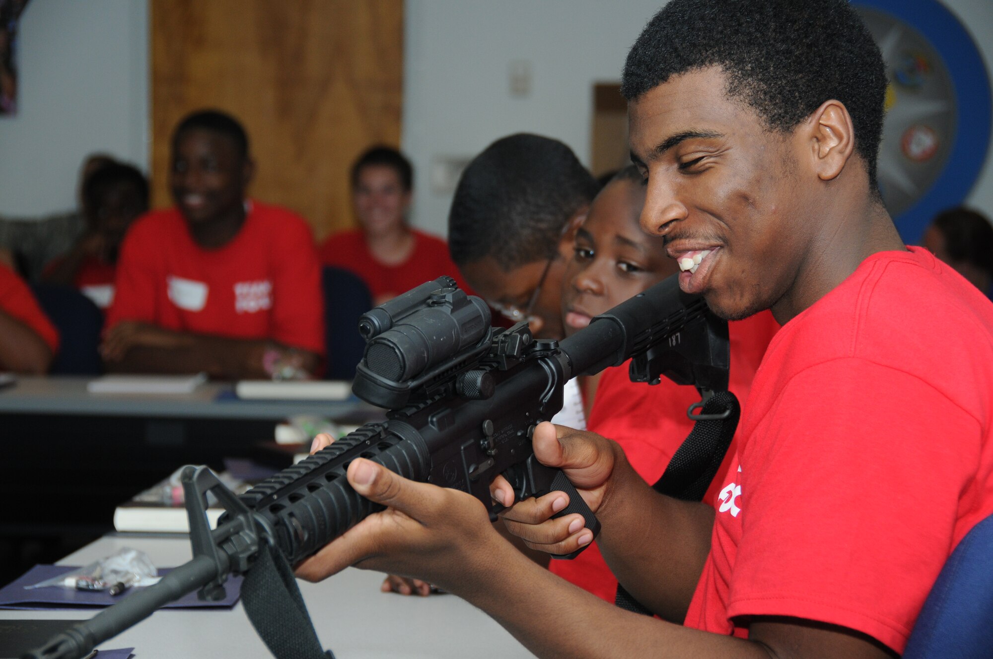 Seventeen-year-old Donald Morgan, son of Laneeka Morgan of Biloxi, holds an M4 Carbine rifle as members of the 81st Security Forces Squadron briefs the members of Team Focus on the various weapons used for deployment missions in the Air Force during career night July 16, 2012, at the Sablich Center, Keesler Air Force Base, Miss. The mission of Team Focus is to provide a year-round program of support, encouragement and values that foster the development of life skills in young men ages 10-18 without a father figure in their lives, bridging the fatherless gap and supporting the family structure.  (U.S. Air Force photo by Kemberly Groue)
