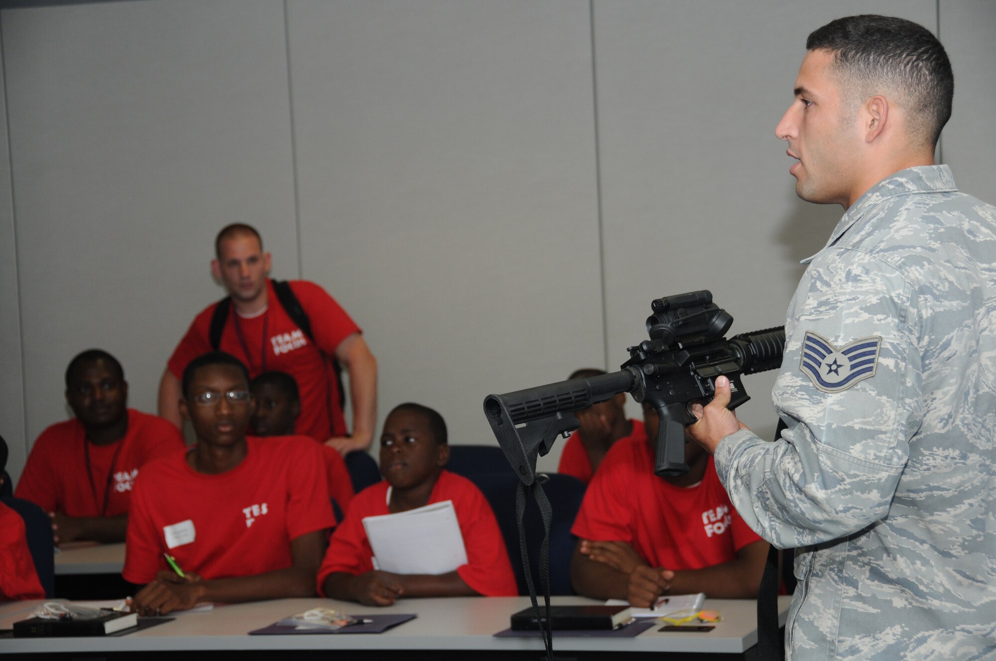 Staff Sgt. Christopher Hernandez, 81st Security Forces Squadron combat arms, briefs members of Team Focus on an M4 Carbine rifle and other weapons used for deployment missions in the Air Force during career night July 16, 2012, at the Sablich Center, Keesler Air Force Base, Miss. The mission of Team Focus is to provide a year-round program of support, encouragement and values that foster the development of life skills in young men ages 10-18 without a father figure in their lives, bridging the fatherless gap and supporting the family structure.  (U.S. Air Force photo by Kemberly Groue)
