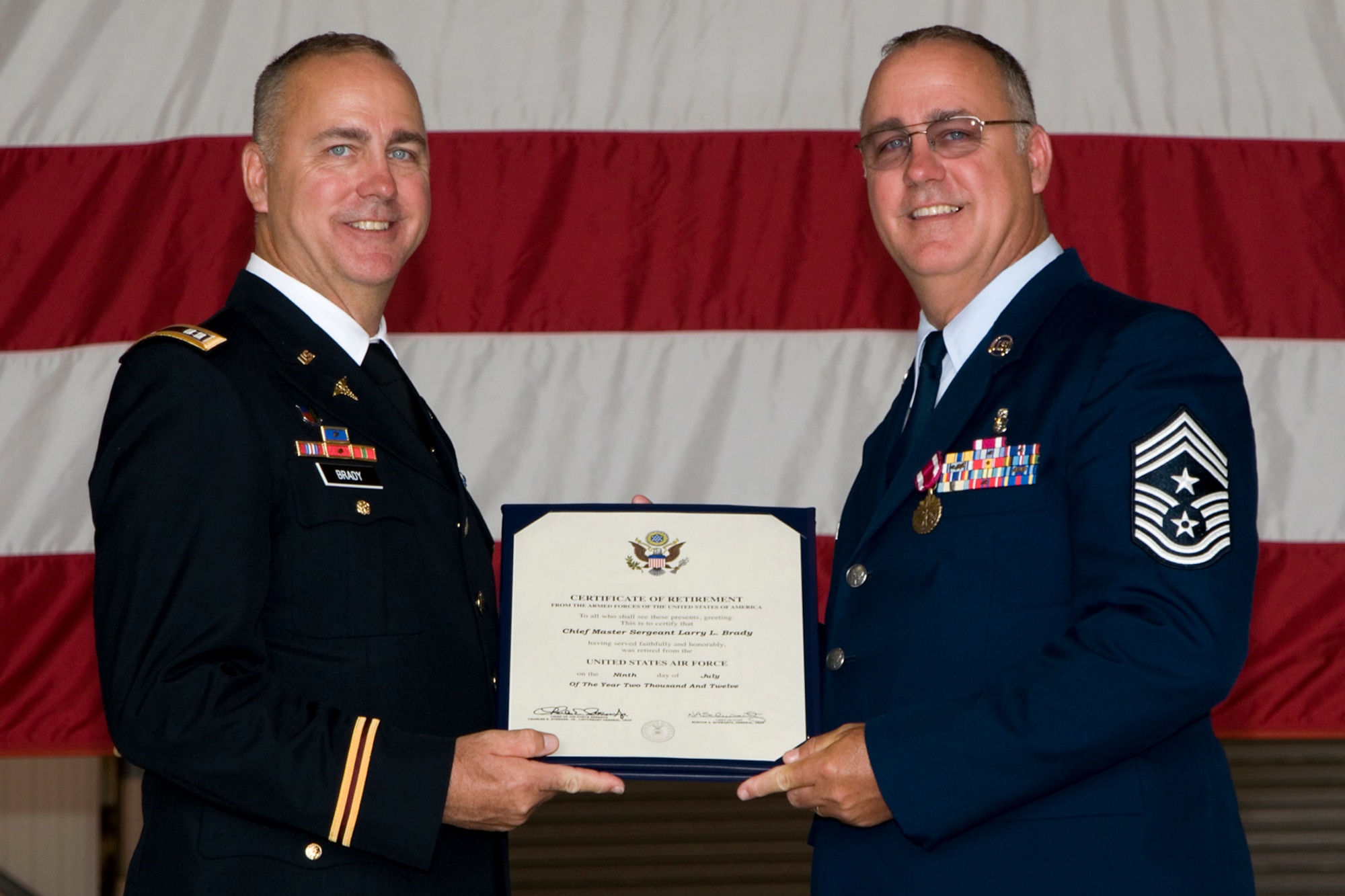 GRISSOM AIR RESERVE BASE, Ind. -- Chief Master Sgt. Larry Brady, former 434th Air Refueling Wing command chief, receives his certificate of retirement from his brother Capt. Garry Brady, a flight surgeon with the 4-3 Aviation Regiment, during a ceremony at Grissom July 8. Chief Brady retired after 28 years of service. (U.S. Air Force photo/Senior Airman Andrew McLaughlin)