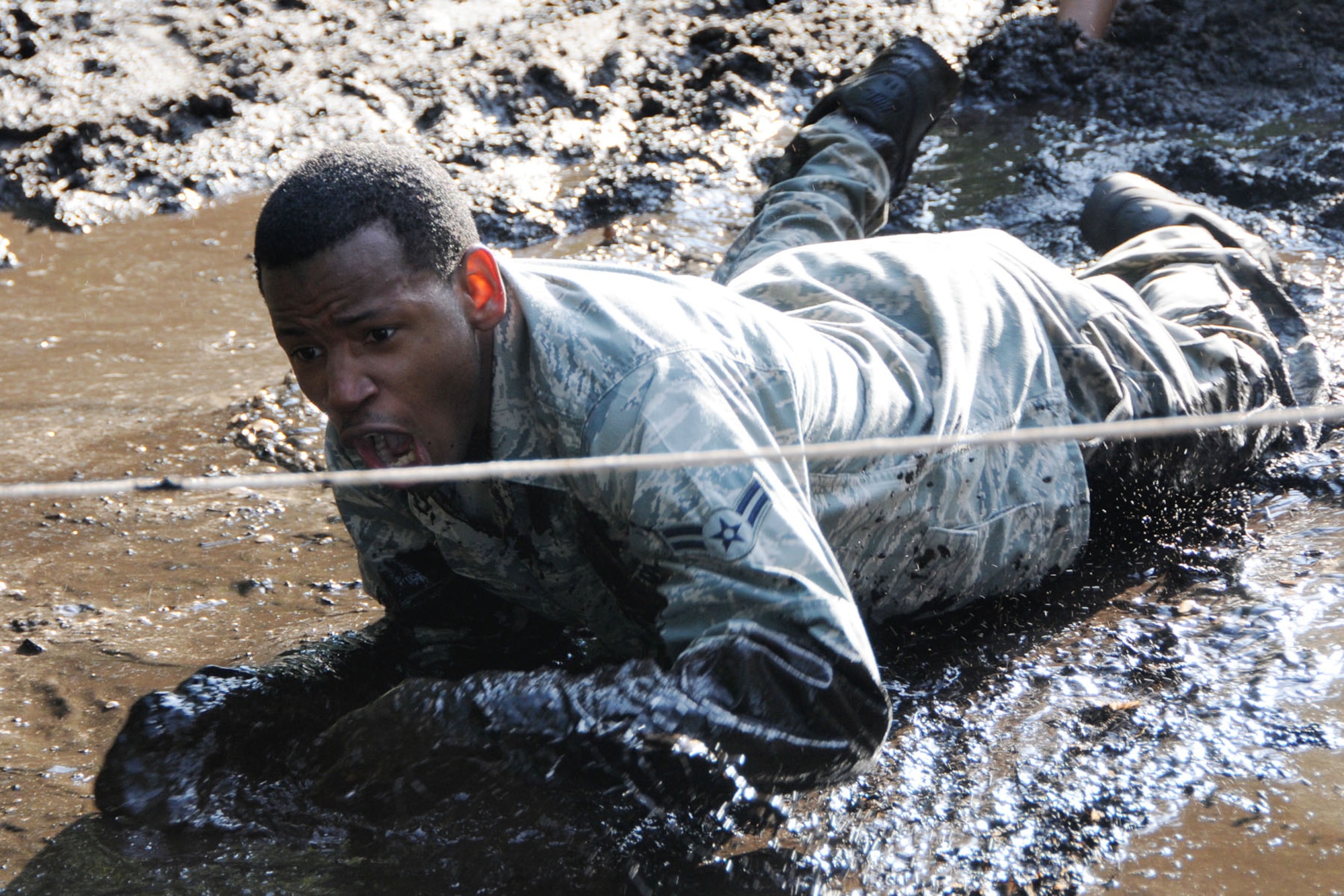 HANSCOM AIR FORCE BASE, Mass. – Airman 1st Class Patrick Haire low crawls through the mud during Warrior Day July 11. Members of the 66th Air Base Group and tenant organizations participated in this monthly event. The next Warrior Day, which is open to all Hanscom members, will be held Aug. 1. (U.S. Air Force photo by Linda LaBonte Britt)
