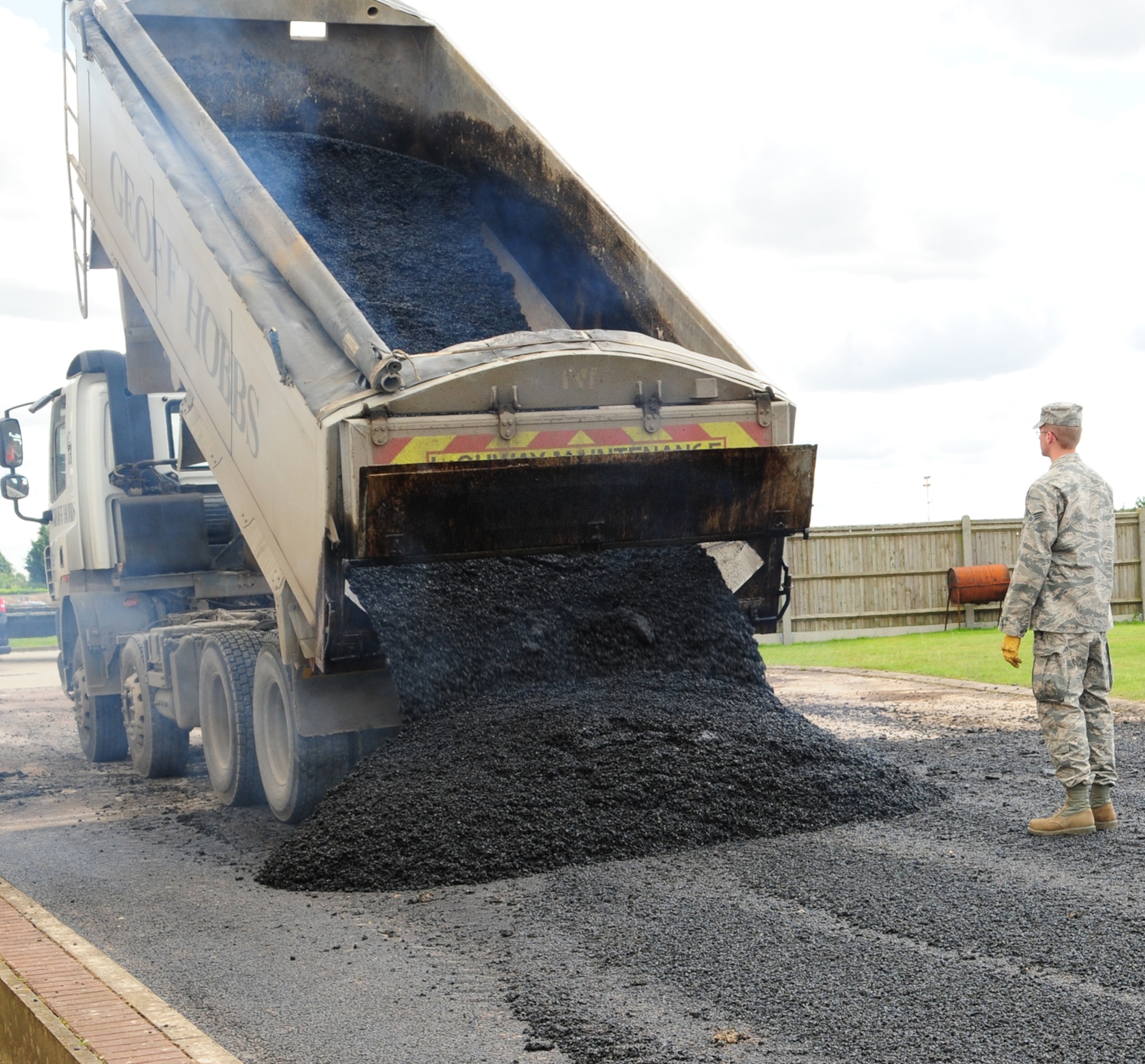 RAF MILDENHALL, England – A contactor empties a pile of steaming hot asphalt onto an area where a section of road is being resurfaced near the 100th Logistics Readiness Squadron compound July 12, 2012. The resurfacing project was carried out by both active duty members from the 100th Civil Engineer Squadron and reservists from the 419th Civil Engineer Squadron, Hill Air Force Base, Utah, who spent two weeks here recently. The temperature of the asphalt starts out at 387 degrees Fahrenheit when leaving the manufacturing plant, and when it is emptied from the truck, the temperature is approximately 325 degrees Fahrenheit. The asphalt has to be at a high temperature so it is malleable and can be easily moved around and smoothed out. Once it drops to 180 degrees Fahrenheit, it can then be driven on. (U.S. Air Force photo/Karen Abeyasekere)