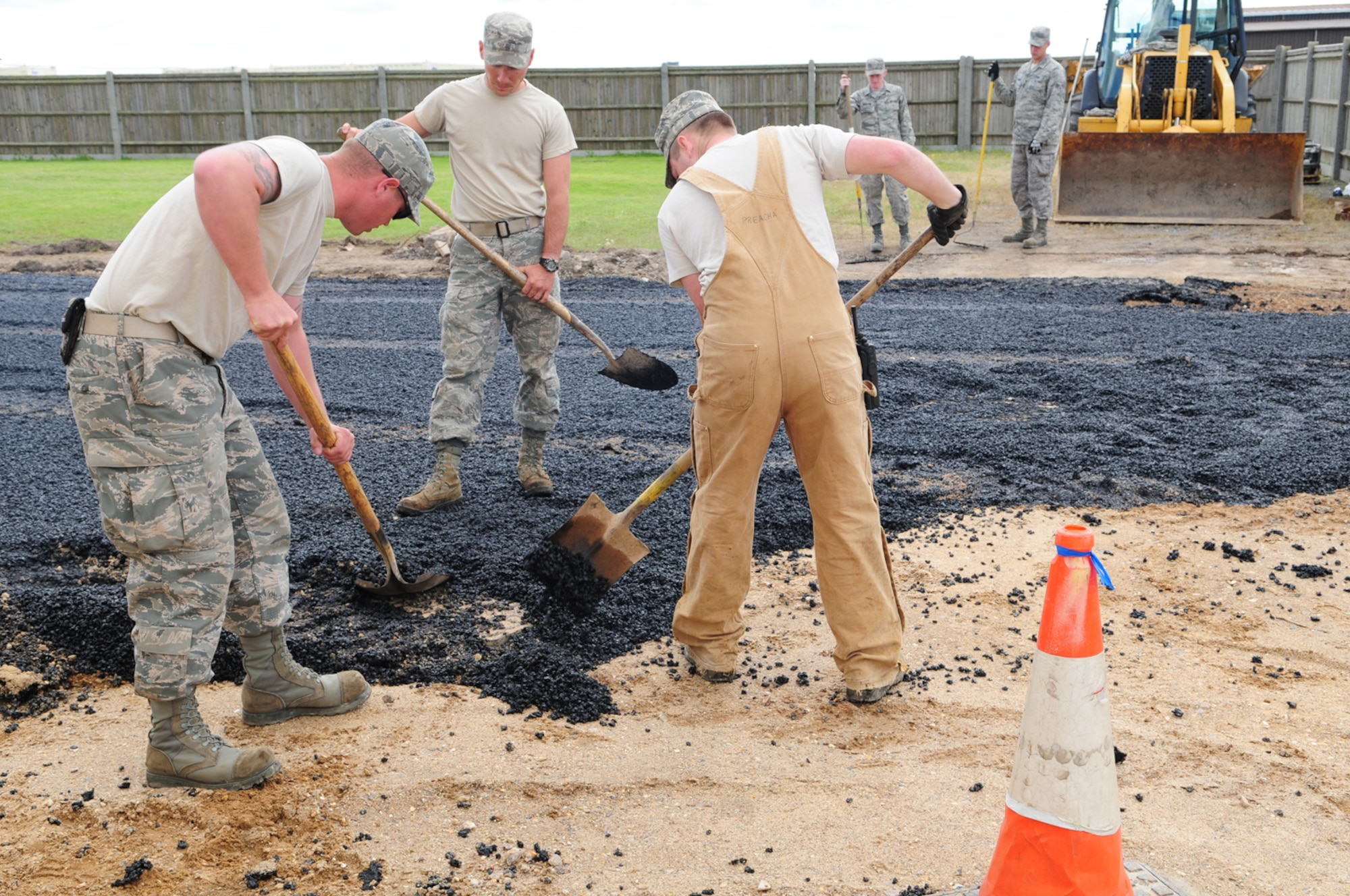 RAF MILDENHALL, England – Senior Airman Kevin Alexander, Airman 1st Class Stephen Beasley, both 419th Civil Engineer Squadron reservists, Hill Air Force Base, Utah, and Senior Airman Billy Crocker, 100th Civil Engineer Squadron, work together to smooth out a pile of asphalt July 12, 2012. Fifty-two reservists from Hill AFB spent two weeks at RAF Mildenhall, training alongside active duty members from 100th CES, and bringing their own skills to share. (U.S. Air Force photo/Karen Abeyasekere)
