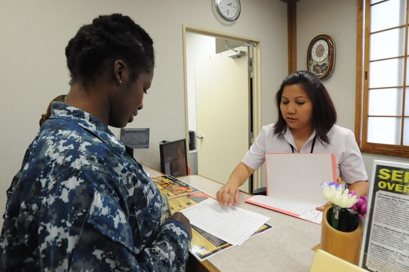 Sharon Williams, right, Misawa Air Base Information, Tickets and Travel transportation clerk, assists a sailor at Misawa Air Base, Japan, July 18, 2012. As the transportation clerk, Williams is in charge of preparing tour materials for the bus drivers and tour guides and schedules hotel reservations for tourists. Williams also educates curious travelers of the best tourist attractions, and helps make the travel experience smooth for military members wanting to explore Japan. The ITT office is open Monday to Friday from 9 a.m. to 6 p.m. On Saturdays, the shop is open from 10 a.m. to 2 p.m. (U.S. Air Force photo by Airman 1st Class Kenna Jackson/Released)