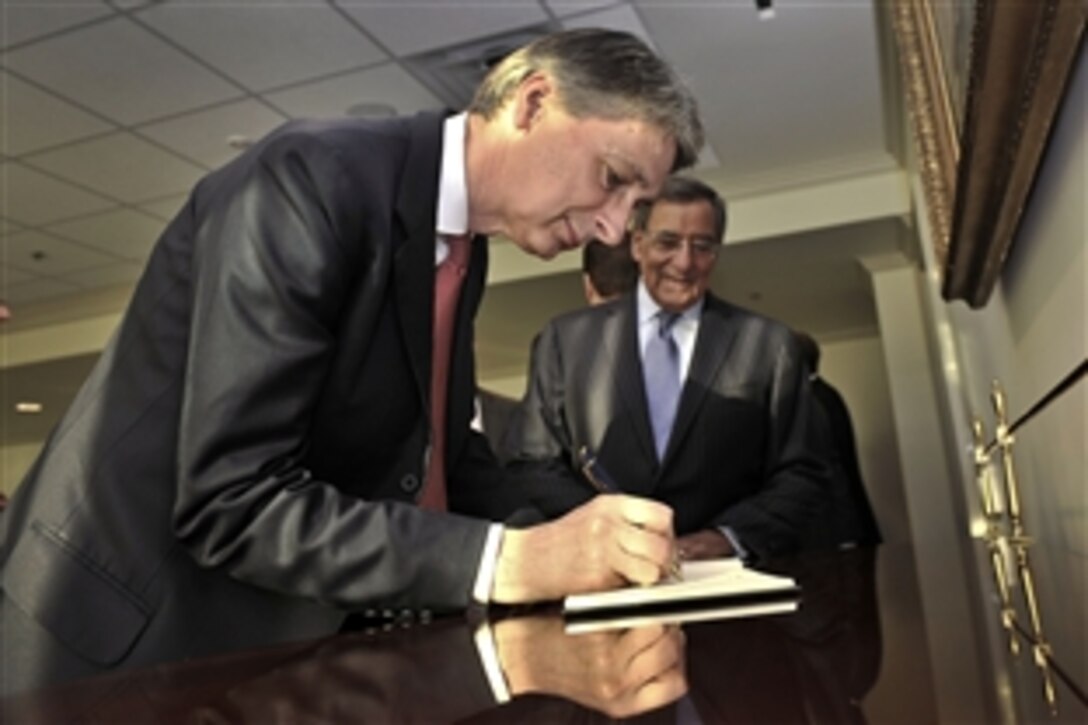 British Defense Secretary Philip Hammond signs the guestbook as U.S. Defense Secretary Leon E. Panetta watches at the Pentagon, July 18, 2012.