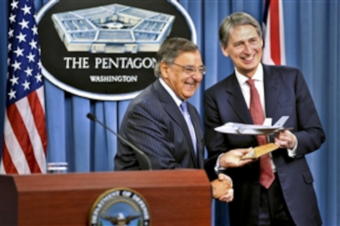 U.S. Defense Secretary Leon E. Panetta hands a model of the F-35 Joint Strike Fighter to British Defense Secretary Philip Hammond in a symbolic gesture to mark the first delivery of the aircraft to British forces as they hold a press conference at the Pentagon, July 18, 2012.