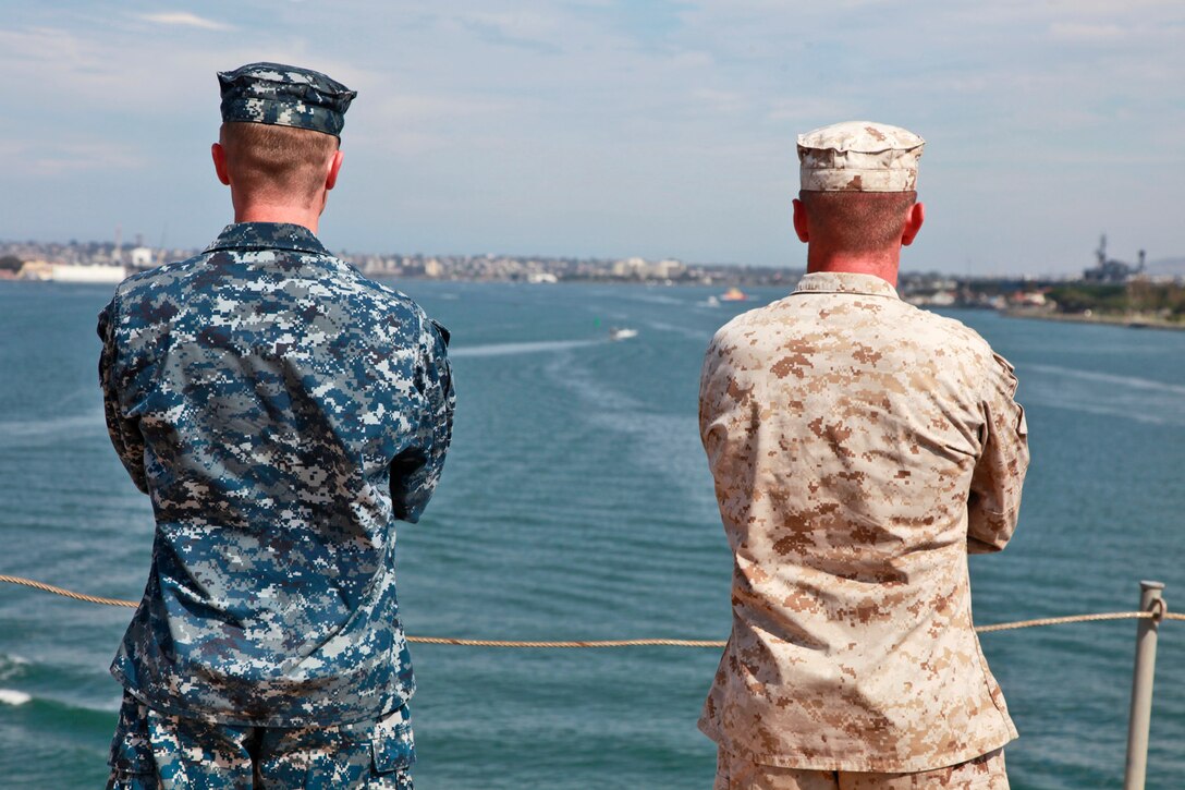 A sailor and Marine stand on the flight deck of the USS Peleliu as it leaves San Diego, July 18, beginning Composite Unit Training Exercise (COMPTUEX) 2012. The pre-deployment exercise will evaluate the ARG’s ability to conduct integrated military operations and support the 15th Marine Expeditionary Unit as it conducts training operations at sea and ashore in a realistic training environment.