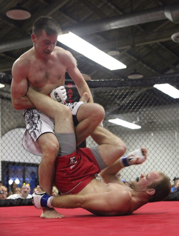 (Left) Cpl. Nick Bilak, a Marine from Marine Corps Base Camp Lejeune with Wrights Extreme Martial Arts, locks Michael Cannon ankle during the Battle in the South IV event hosted at the Coastline Convention Center in Wilmington, N.C., July 14. The event featured 12 bouts and two of them included devil dogs from MCB Camp Lejeune.