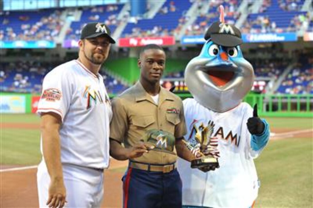 U.S. Marine Corps Corporal Luchmy Luc, a 22-year-old native of Hollywood, Fla., stands with Heath Bell, a relief pitcher for the Miami Marlins, and Billy the Marlin, the team's mascot, after being recognized as Soldier of the Game, June 11. The Marlins kicked off a three-game series with the Boston Red Sox with a salute to the troops during one of their Military Monday baseball game. Luc is an administrative clerk with U.S. Marine Corps Forces, South and was recognized for his career accomplishments and service to his country and community. 
