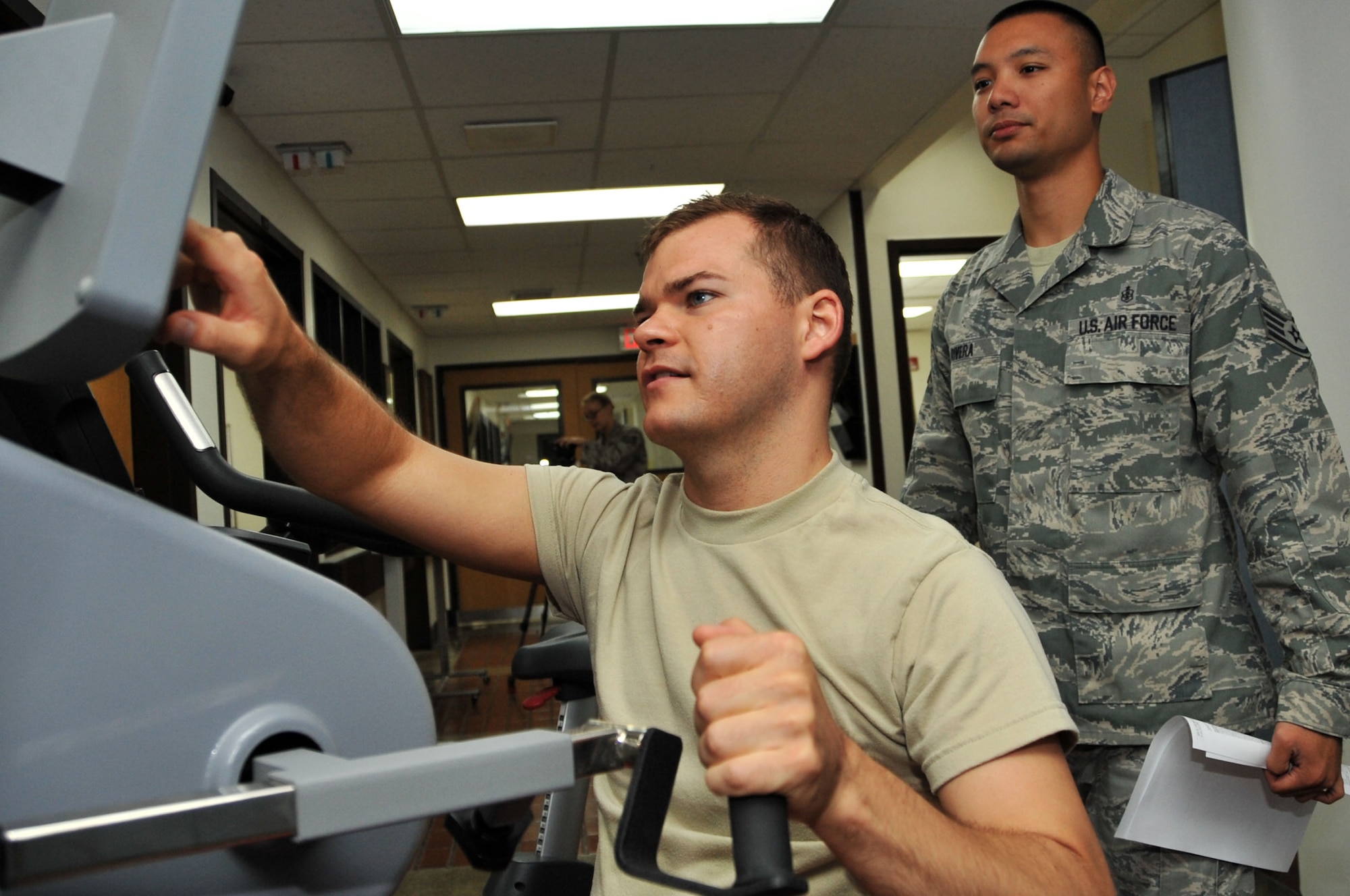 Senior Airman Marshall Hunsaker sets the resistance on an upper body exerciser while Staff Sgt. Kenneth Rivera monitors him in the physical therapy clinic at Osan Air Base, Republic of Korea, July 19, 2012. Hunsaker attends routine sessions at the 51st Medical Operations Squadron after having surgery for a torn labrum in his left shoulder. Hunsaker is a 51st Fighter Wing Public Affairs broadcaster, and Rivera is a 51st MDOS physical therapy craftsman. (U.S. Air Force photo/Staff Sgt. Stefanie Torres)
