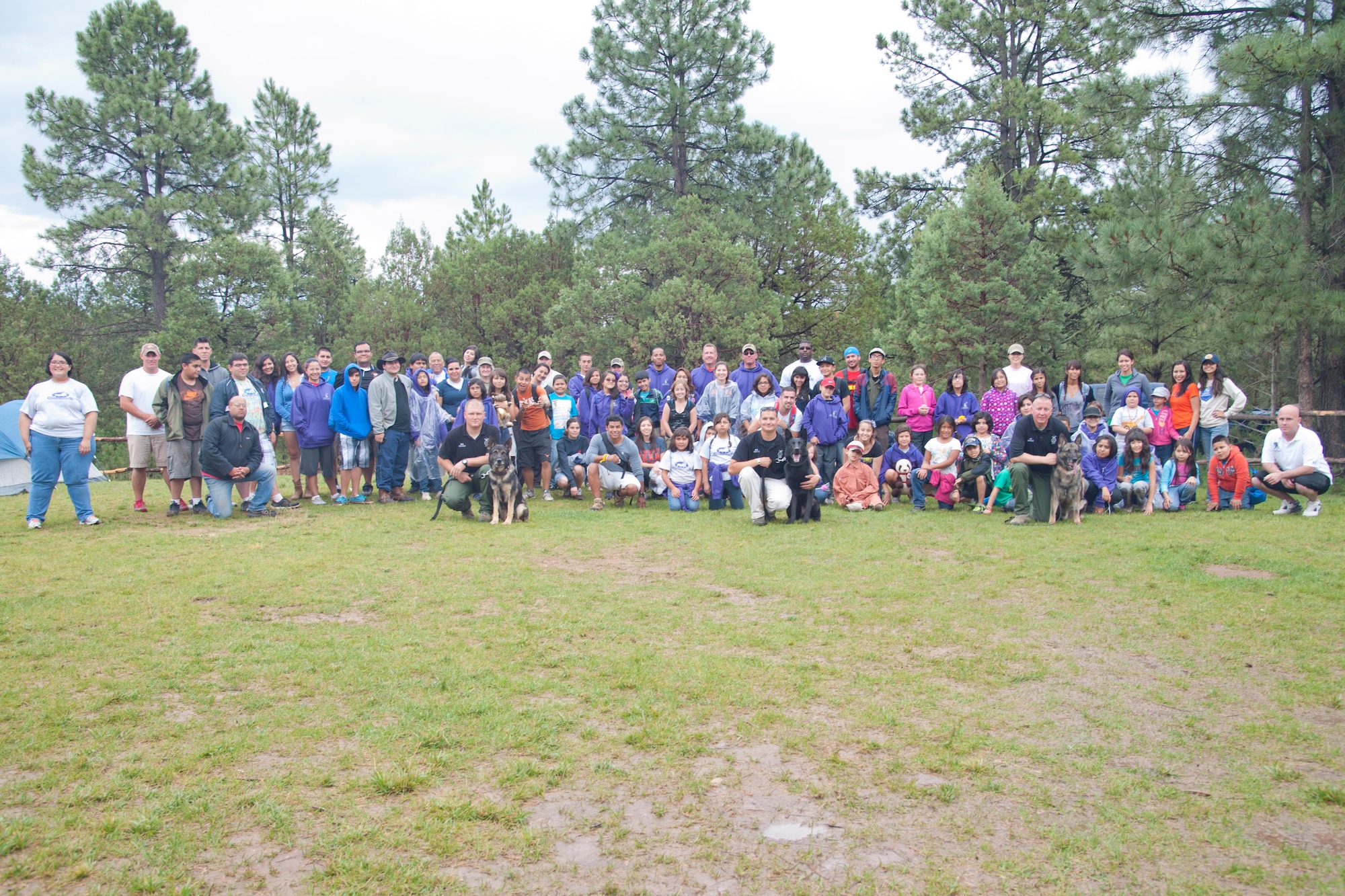 Members of the 49th Security Forces Squadron pose for a photo with participants in the Candlelighters for Children with Cancer program at the Mayhill, N.M., Camp of the Tall Pines July 17. Members of the 49th SFS demonstrated the military working dogs’ capabilities to participants in the Candlelighters for Children with Cancer program as a way of boosting the children’s morale and giving back to the community. (U.S. Air Force Photo by Airman 1st Class Anthony M. Ward/Released)