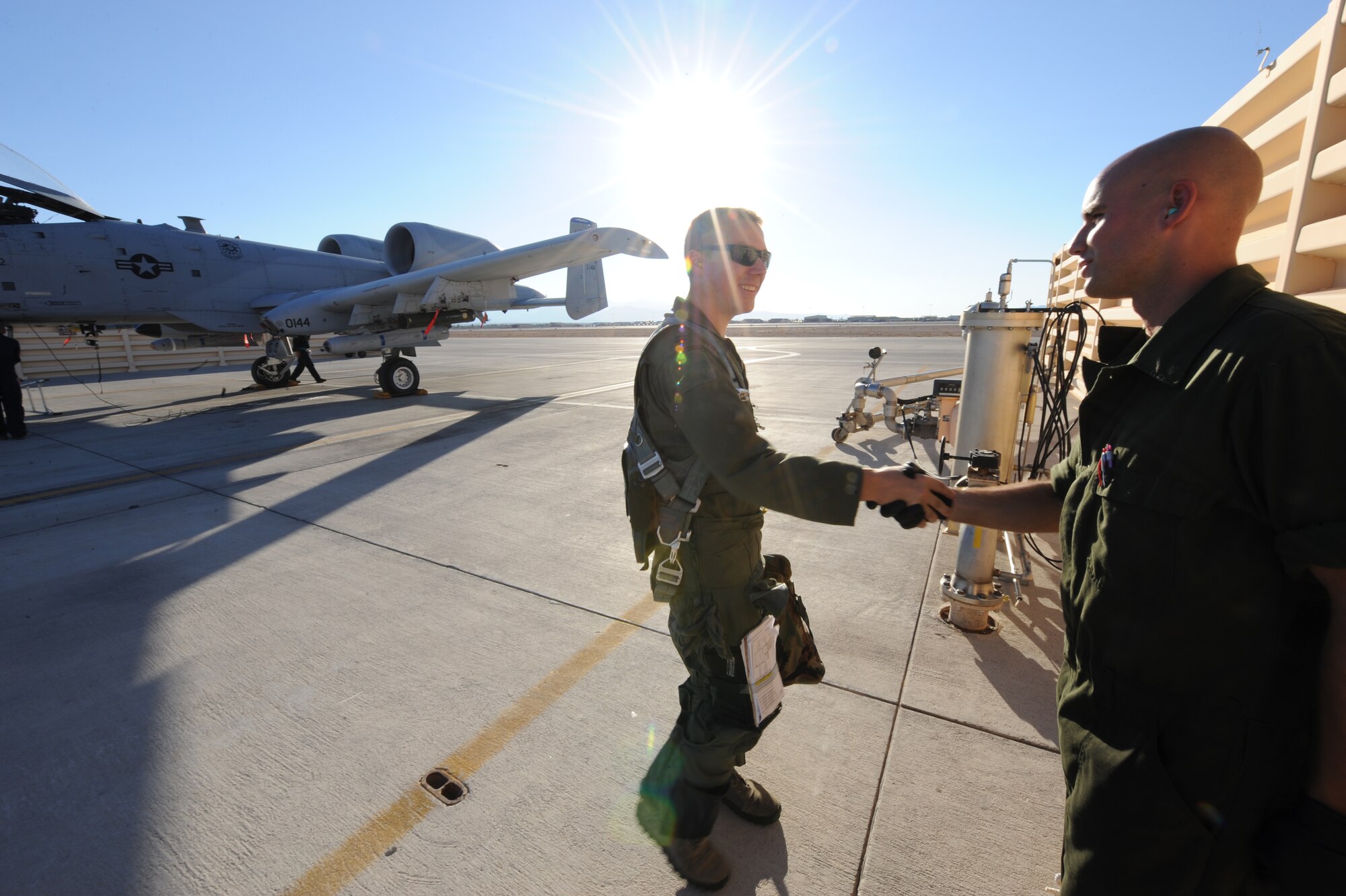 U.S. Air Force Capt. Ian Whiteman, an A-10 pilot with the 74th Fighter Squadron at Moody Air Force Base, Ga., shakes hands with Staff Sgt. Nicholas Nelson, A-10 Crew Chief with the 74th Aircraft Maintenance Unit, July 16, 2012, at Nellis Air Force Base, Nev., following a training mission during exercise Red Flag 12-4.  Crew chiefs perform walk around inspections with the pilot before and after a flight and correct any maintenance issues prior to the next mission. (U.S. Air Force photo by Master Sgt. Sonny Cohrs/Released)   