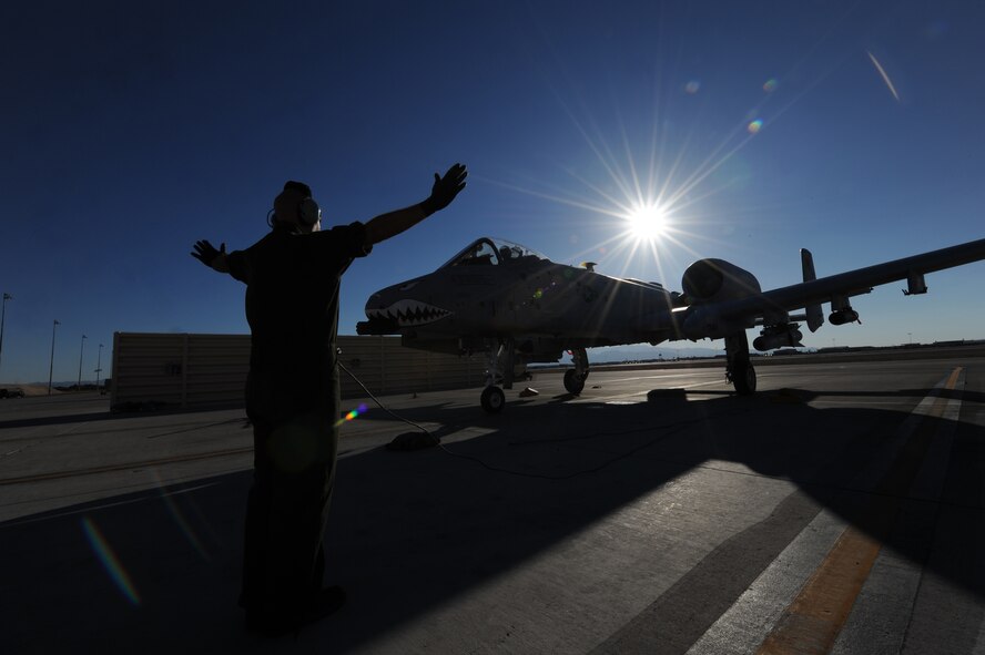 U.S. Air Force Staff Sgt. Nicholas Nelson, a crew chief with the 23d Aircraft Maintenance Squadron, 74th Aircraft Maintenance Unit, guides an A-10C Thunderbolt II into its parking space at Nellis Air Force Base, Nev., following a Red Flag training mission July 16, 2012.  Temperatures reach in excess of 100 degrees in the Nevada desert, and 74th AMU maintainers are launching aircraft around the clock during the exercise. Fourteen A-10s are deployed to Nellis from Moody Air Force Base, Ga., along with more than 200 aircrew, maintainers and support personnel.   (U.S. Air Force photo by Master Sgt. Sonny Cohrs/Released)   