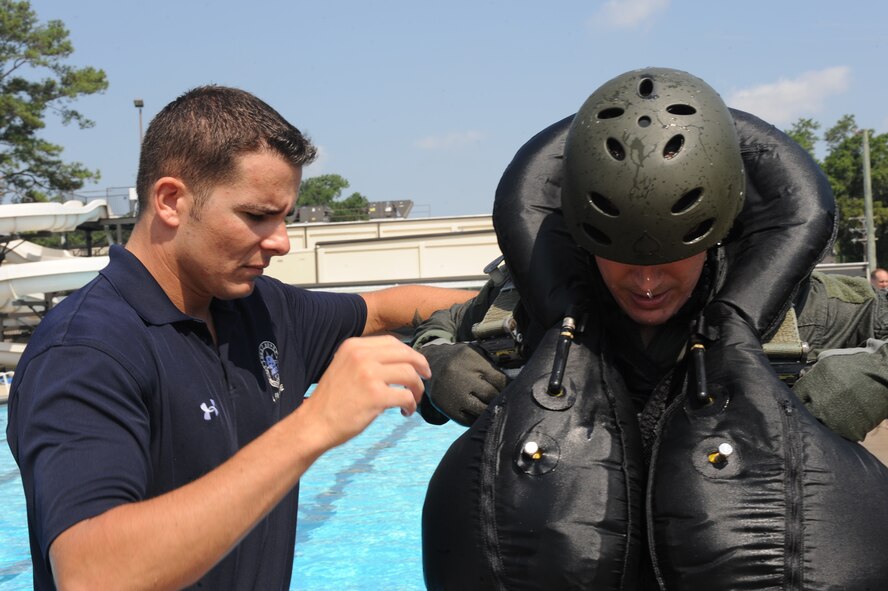 U.S. Air Force Staff Sgt. Justin Pishner (left) 4th Operations Support Squadron survival, evasion, resistance and escape specialist helps Maj. Don Haley, 334th Fighter Squadron pilot, don a harness during a SERE water survival course at Seymour Johnson Air Force Base, N.C., July 18, 2012. (U.S. Air Force photo/Airman 1st Class John Nieves Camacho/Released)