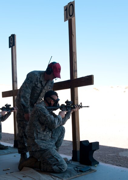 Staff Sgt. Chris Ley, 49th Security Forces Squadron Combat Arms Training and Maintenance instructor, coaches Airman 1st Class Zachary Harter, 49th Civil Engineer Squadron structures apprentice, as he shoots the M-4 rifle at the Holloman Air Force Base, N.M., Combat Arms Training and Maintenance range July 18. Before any Holloman Airman goes on a deployment, they must complete the weapons qualifications course, which includes a weapons-familiarization training block taught in the classroom and at the shooting range. To qualify, Airmen must shoot targets at 7, 15 and 25 meters, while going through a combination of multiple target drills, threat discrimination, and burst-fire sessions. (U.S. Air Force photo by Airman Leah Ferrante/Released)
