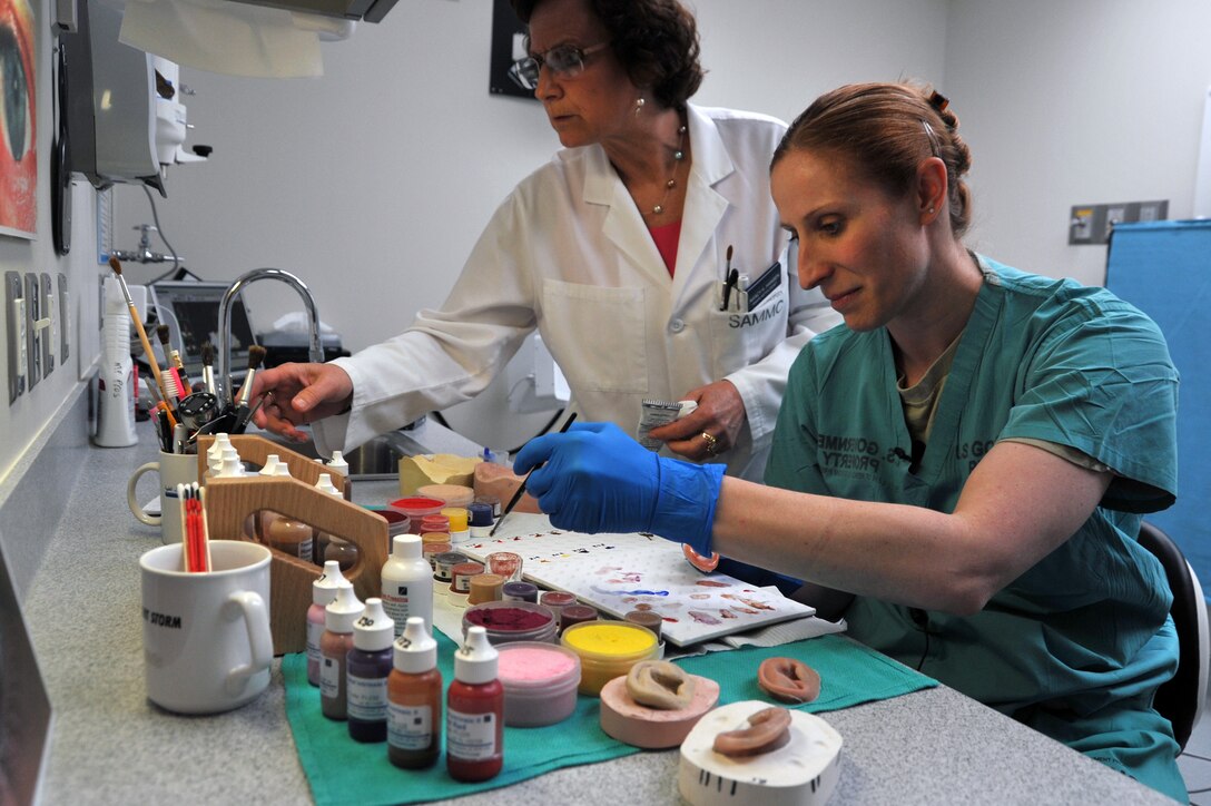Ret. Master Sgt. Nancy Hansen and Capt. Sarra Cushen paint prosthetic ears for wounded warriors at San Antonio Military Medical Center on July 11, 2012. Hansen is one of two anaplastology's in the DOD and Cushen is beginning her maxillofacial prosthetic fellowship which is a year long program. (U.S. Air Force photo/Desiree N. Palacios)