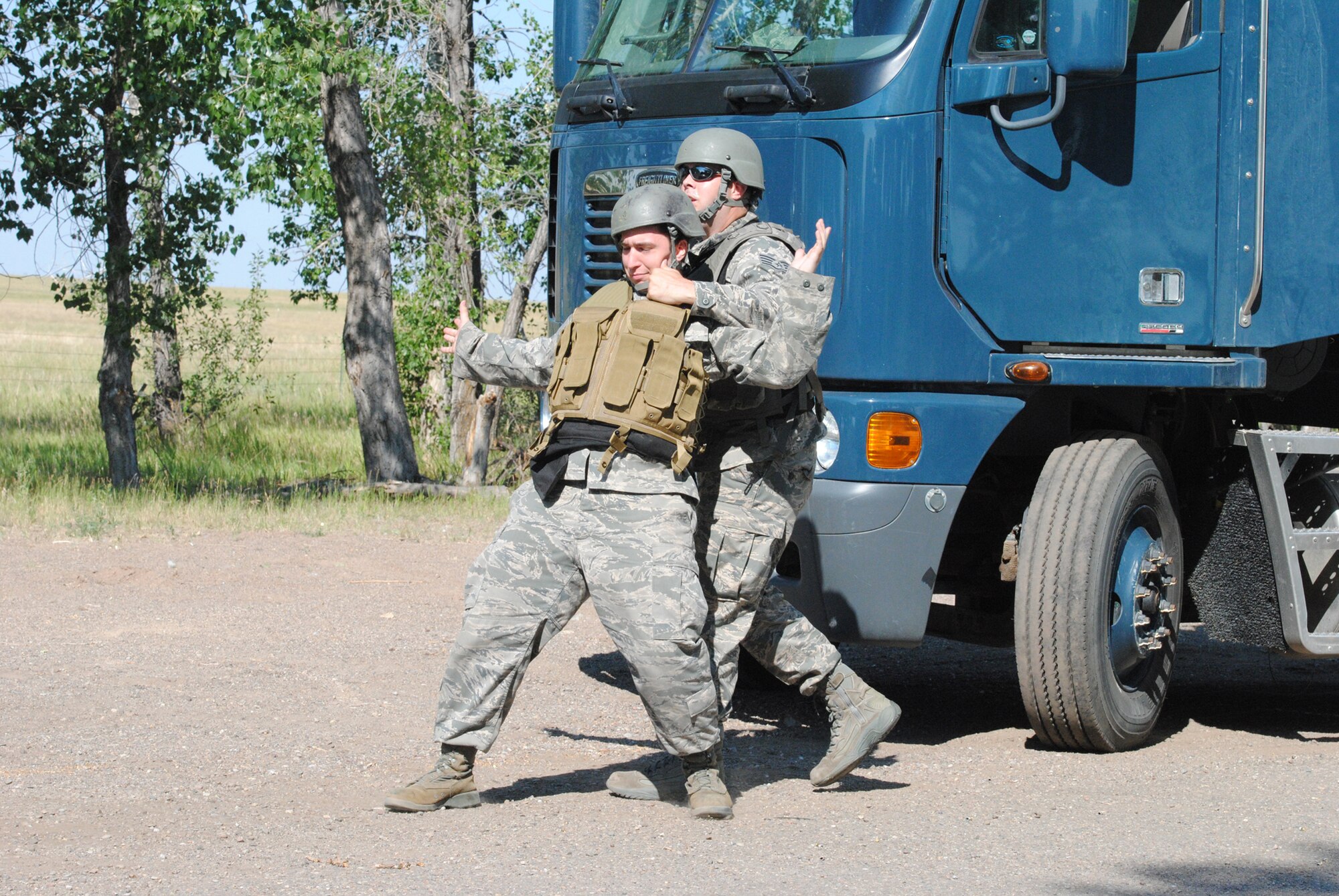 Staff Sgt. Perry Sumrall, 341st Maintenance Operations Squadron special vehicle operations instructor, right, seizes Senior Airman Christopher Balser, 341st MOS technician, during a training exercise at the Warrior Launch Facility on July 12. Airmen will eventually have the opportunity to see the filmed scenario on the EST 2,000 Trainer and will have to decide how to handle a situation where a Payload Transporter van driver acts hostile. (U.S. Air Force photo/Airman 1st Class Katrina Heikkinen)