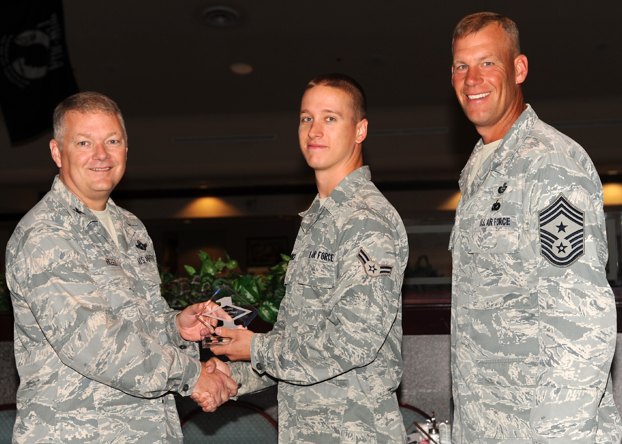 Col. Scott Rizer 319th Air Base Wing vice commander, presents Airman 1st Class Alexander Shiverick, 319th Civil Engineer Squadron, with a Diamond Sharp Award July 19, 2012, on Grand Forks Air Force Base, N.D., accompanied by 319th ABW Command Chief Master Sgt. David Carlson.  The Diamond Sharp Award is given to Airmen who epitomize service before self and strive for excellence at work and off duty.  (U.S. Air Force photo by Airman 1st Class Xavier Navarro)  