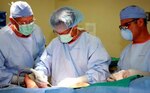 Lt. Cmdr. Christopher Burns, U.S. Army Institute of Surgical Research Burn Center surgeon, center, uses a surgical instrument to prepare a wound for surgery while, Col. Evan M. Renz, burn center director, left, and Spc. Dennis Ortiz, operating room technician, look on during the first surgery procedure performed in the new Burn Center OR, May 25, 2012, at the new consolidated tower of the San Antonio Military Medical Center.
(U.S. Army photo by Steven Galvan)