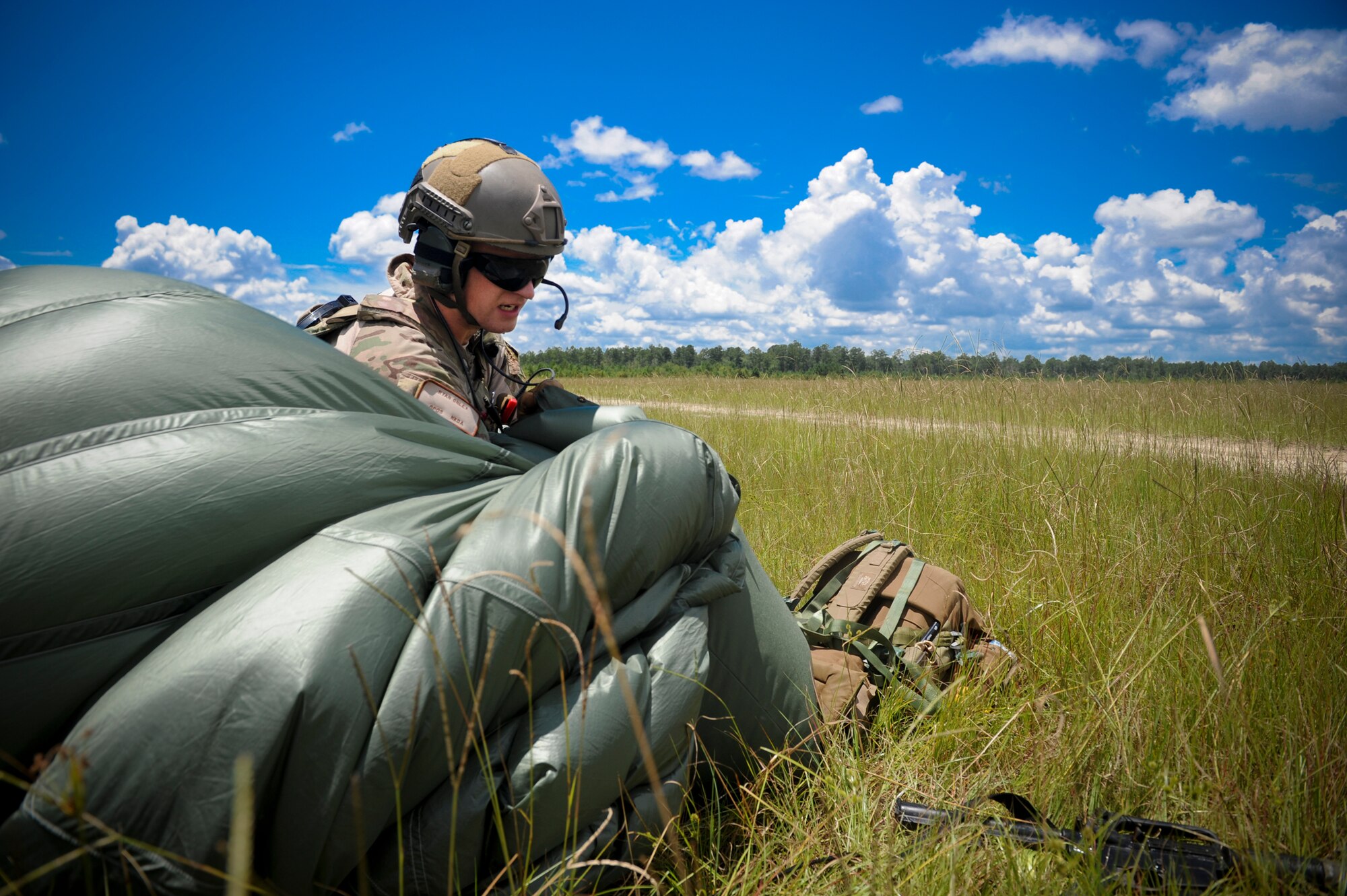U.S. Air Force Staff Sgt. Ryan Onley, 38th Rescue Squadron pararescueman, packs his parachute into a bag after parachuting from an HC-130P Combat King at Moody Air Force Base, Ga., July 16, 2012. After packing his parachute, Onley rallied with his team to evaluate their plan of action during a training scenario. (U.S. Air Force photo by Airman 1st Class Douglas Ellis/Released)
