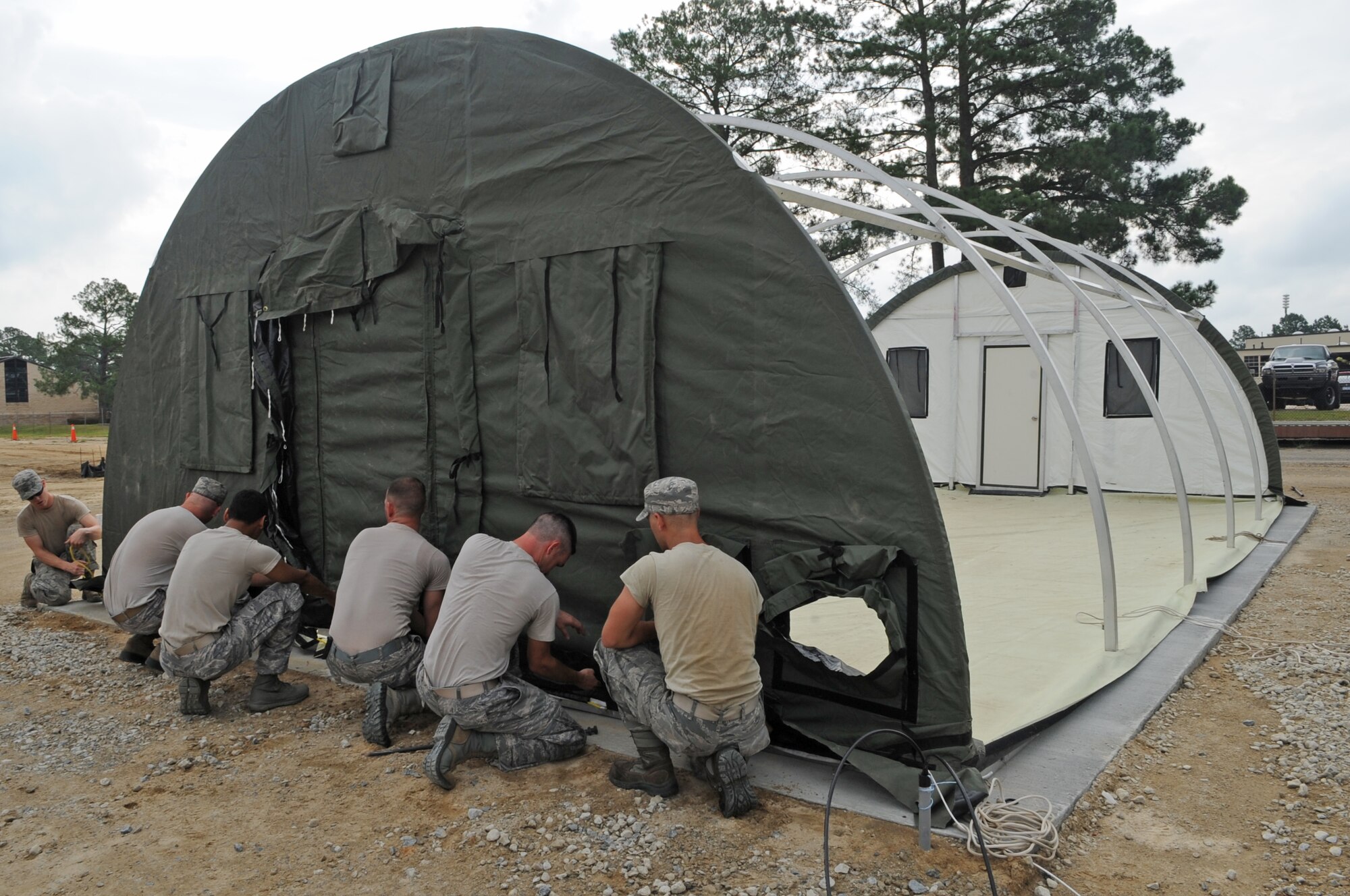 U.S. Air Force Airmen assigned to the 4th Fighter Wing secure the front of a tent on Seymour Johnson Air Force Base, N.C., July 11, 2012. The tents make up a simulated deployed location where Airmen participate in operational readiness training exercises. (U.S. Air Force photo/Airman 1st Class Aubrey Robinson/Released)