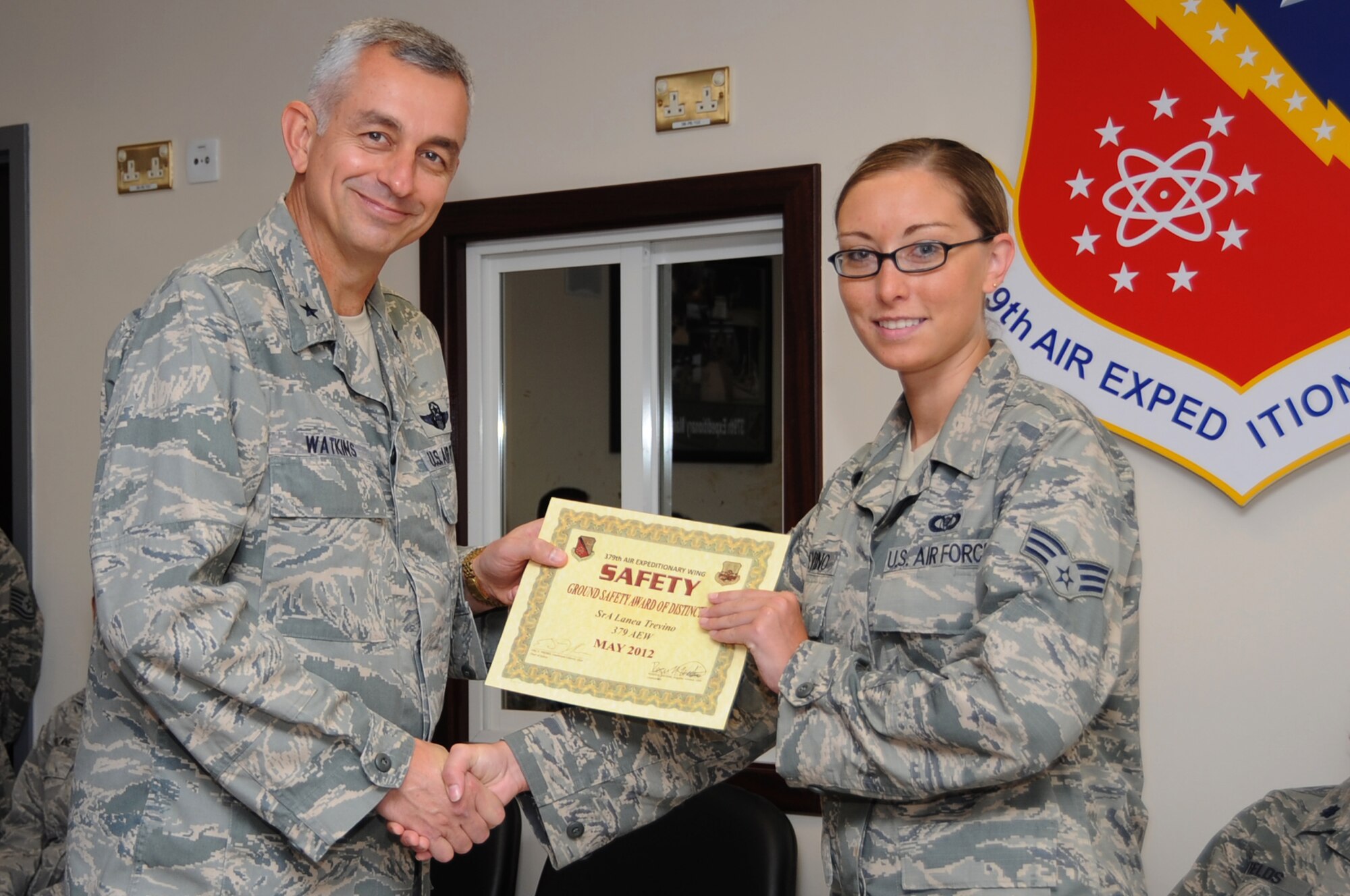 U.S. Air Force Senior Airman Lanea Trevino, 379th Air Expeditionary Wing command post controller, poses with the 379th AEW Commander, Brig. Gen. Roger Watkins, after being recognized for the Ground Safety Award for Distinction, May 2012 in Southwest Asia, July 17, 2012. Trevino discovered a service member unresponsive inside a restroom and quickly took action. Due to her immediate response and dedication to the Wingman concept, the service member made a full recovery. (U.S. Air Force photo/Staff Sgt. Sheila deVera)