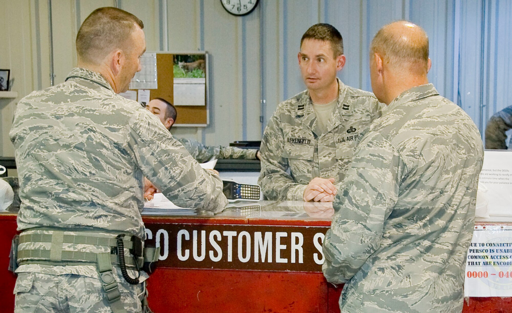 Captain Michael Burkenfield, 379th Expeditionary Force Support Squadron Personnel Support for Contingency Operations commander, assists the customer service team with helping customers July 10, 2012. The customer service team conducts in-processing and out-processing of service members, replacing common access cards, working with home stations to obtain reenlistment paperwork and processing emergency leave. (U.S. Air Force photo/Senior Airman Bryan Swink)