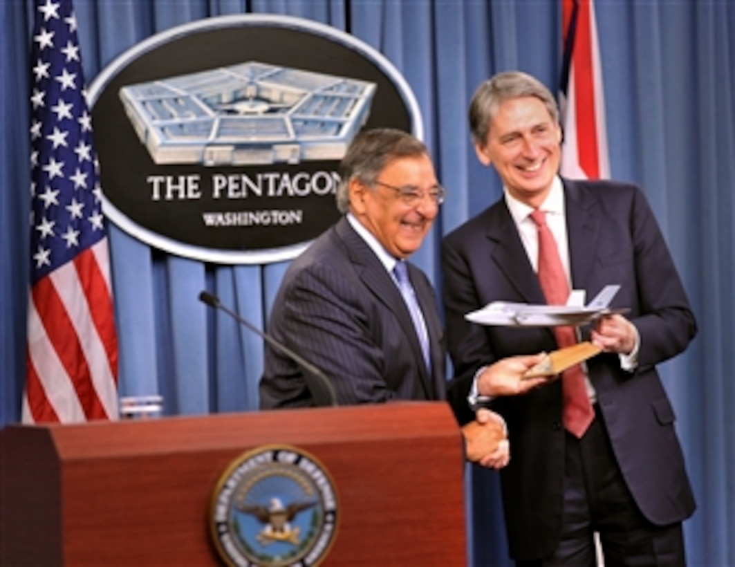 Secretary of Defense Leon E. Panetta presents a model of the F-35 Joint Strike Fighter to the United Kingdom's Secretary of State for Defense Philip Hammond at the beginning of a press conference in the Pentagon on July 18, 2012.  The model exchange is a symbolic gesture that marks the delivery of the first actual aircraft to British forces in Fort Worth, Texas, on July 19th.   