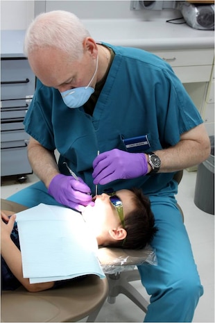 Navy reservist Capt. Richard Burke, pediatric dentist, Naval reserve station Illinois, examines the teeth of his patient, Sebastian T. Pacheco, 4, as part of a routine checkup during Burke's annual active-duty training here July 19, 2012.