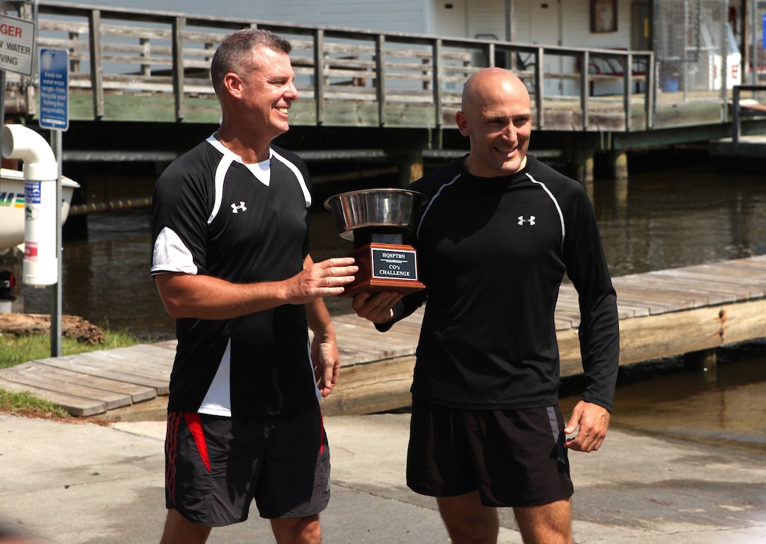 Lt Col. David Bardorf (left), commanding officer of Headquarters and Support Battalion, presents 1st Sgt. Dustin Kazmar, the former first sergeant of Company B, with the Commander’s Cup trophy for winning the paddleboarding relay-race July 20 at Gottschalk Marina aboard Marine Corps Base Camp Lejeune. This competition was the last challenge Kazmar will be participating in.