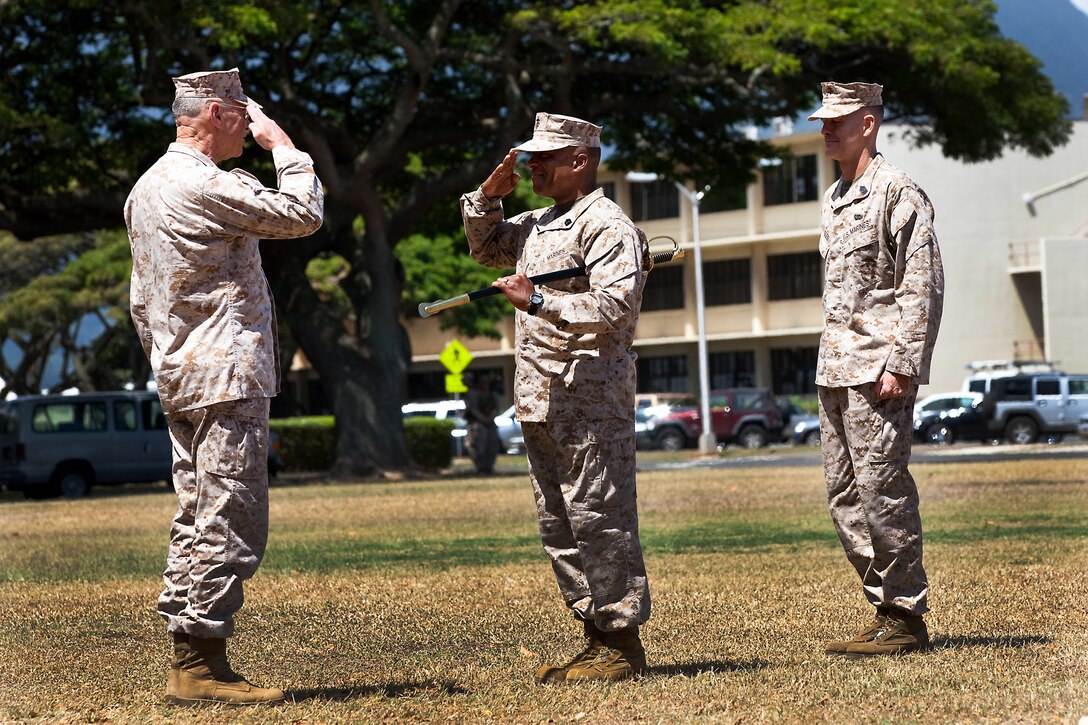 Sgt. Maj. James R. Futrell (center), U.S. Marine Corps Forces, Pacific sergeant major, salutes Lt. Gen. Duane D. Thiessen (left), commander of MarForPac, before passing the noncommissioned officer sword during the relief, appointment and retirement ceremony at Dewey Square here July 19. The transfer of the NCO sword, a symbol of an NCO's ability and prestige as an enlisted leader, signifies the transfer of the sacred trust of the office from one sergeant major to another.  Futrell was replaced by Sgt. Maj. William T. Stables (right).