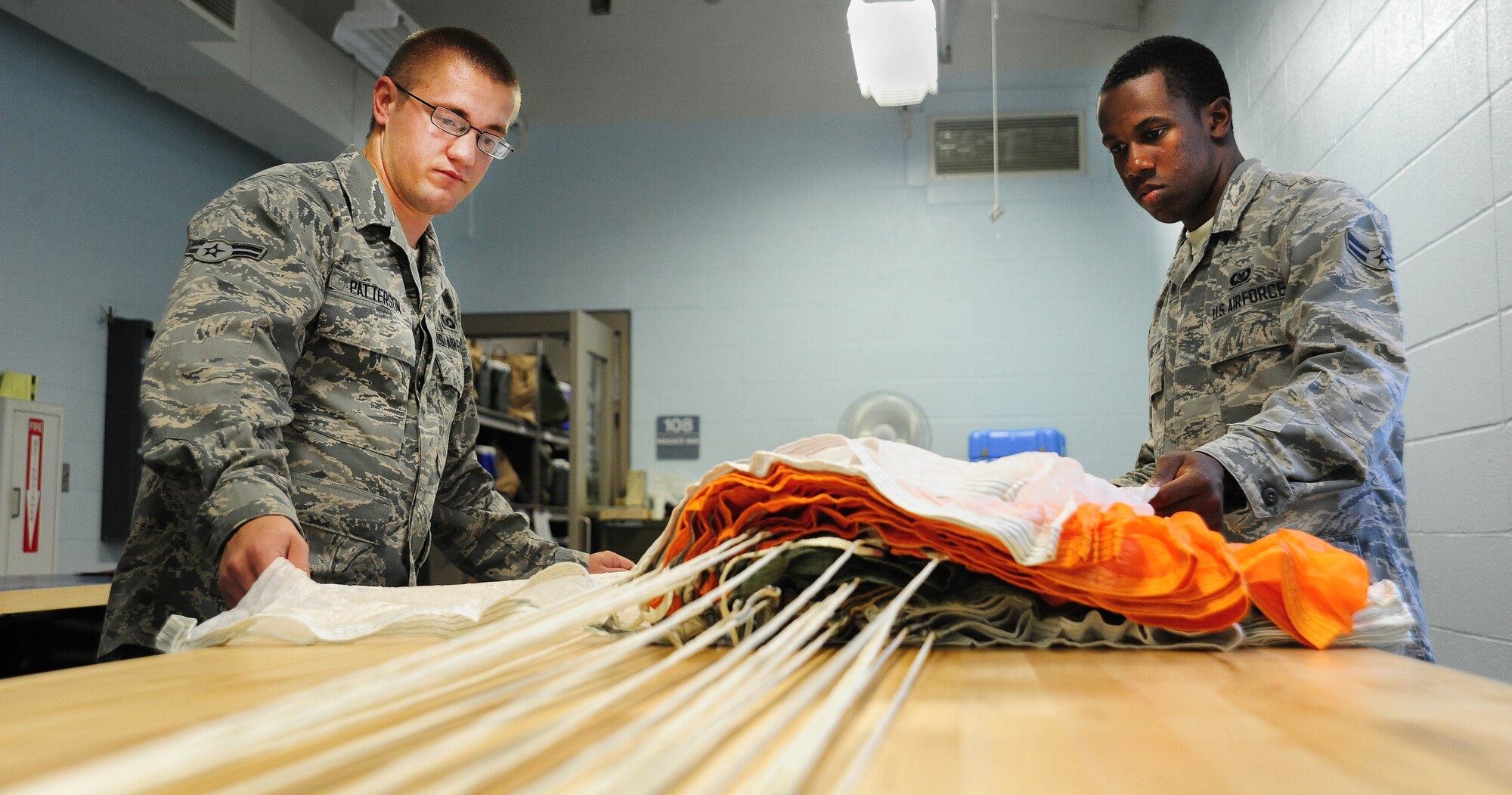 WHITEMAN AIR FORCE BASE, Mo. -- Airman 1st Class Anthony Patterson and Airman 1st Class Dalvin Washington, 509th Operations Support Squadron Aircrew Flight Equipment apprentices, perform maintenance as part of a checklist for packing parachutes July 9. The checklist must be completed when packing parachutes to ensure the parachute is packed correctly and safely. (U.S. Air Force photo/Senior Airman Nick Wilson) (Released)