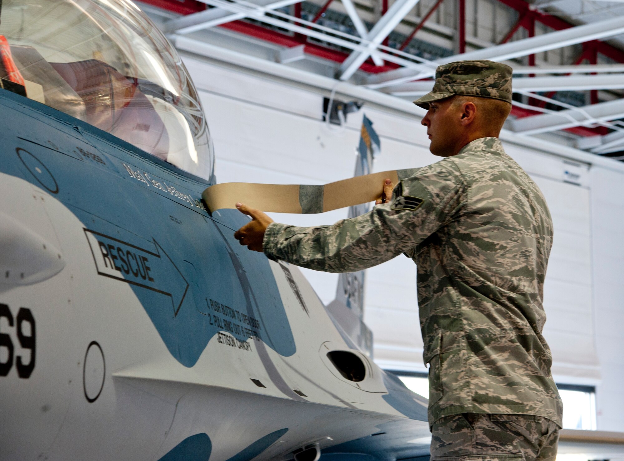 U.S. Air Force Senior Airman Daniel Myles, 57th Aircraft Maintenance Squadron, reveals the name of Maj. Gen. Jeffrey Lofgren, U.S. Air Force Warfare Center commander, during a change of command ceremony July 20, 2012, at Nellis Air Force Base, Nev. Myles is a tactical aircraft maintainer originally from Great Falls, Montana.  (U.S. Air Force photo by Master Sgt. Jason W. Edwards/Released)