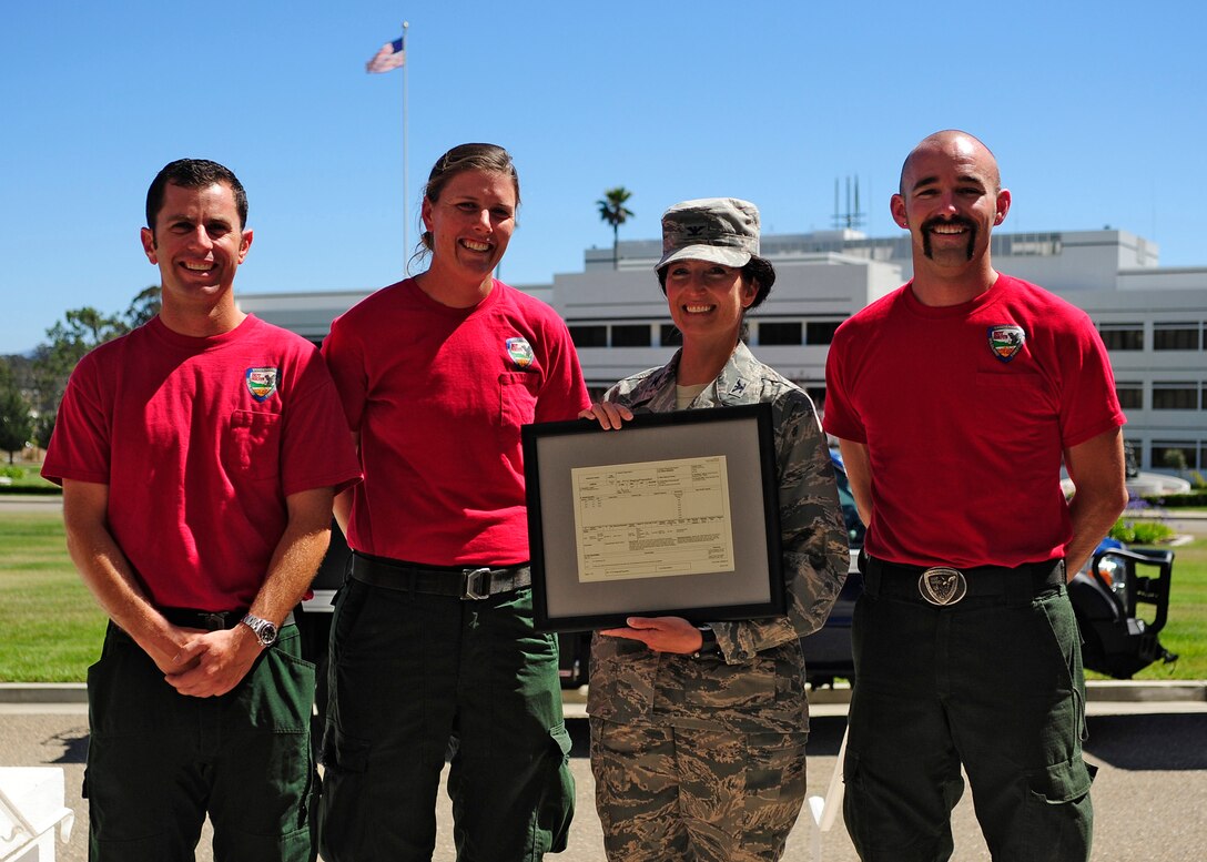 VANDENBERG AIR FORCE BASE, Calif. -- Col. Nina Armagno, 30th Space Wing commander, presents Vandenberg Hot Shots members Cody Lee, Kristin Halbeisen and Jesse Hendricks with their original assignment order to fight the Waldo Canyon Fire in Colorado as a memento for the entire crew. The Hot Shots were fighting wildfires in Colorado and Wyoming, which burned 29,168 acres and destroyed nearly 360 homes in Colorado. (U.S. Air Force photo/Michael Peterson)