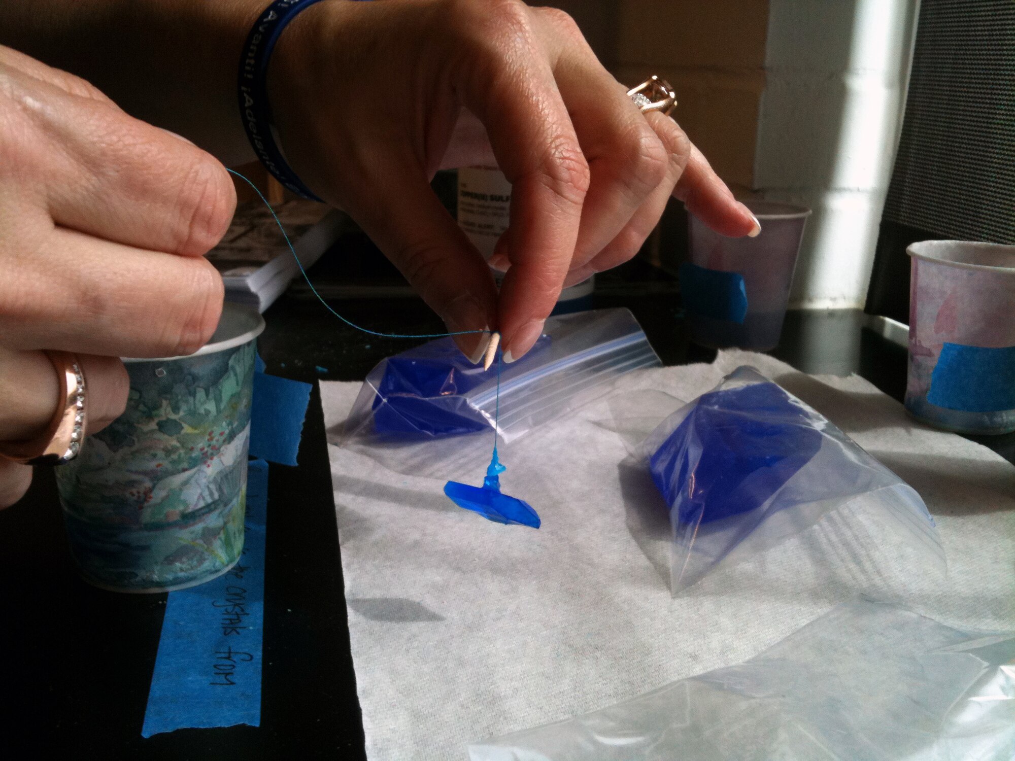 Janet Fenstermacher, teacher from Yorktown High School, Arlington, Va., holds a crystal during an Air Force-sponsored ASM International Materials Camp at Howard University in Washington, D.C., July 13.  At the beginning of the week-long course, Fenstermacher poured a saturated form of copper sulfate into a glass dish and, once seed crystals formed, she tied a thread to the seeds allowing crystals to grow. Fenstermacher is one of 23 teachers who learned how to make science, technology, engineering and math fun for her students. (U.S Air Force photo by 1st Lt. Ashleigh Peck)